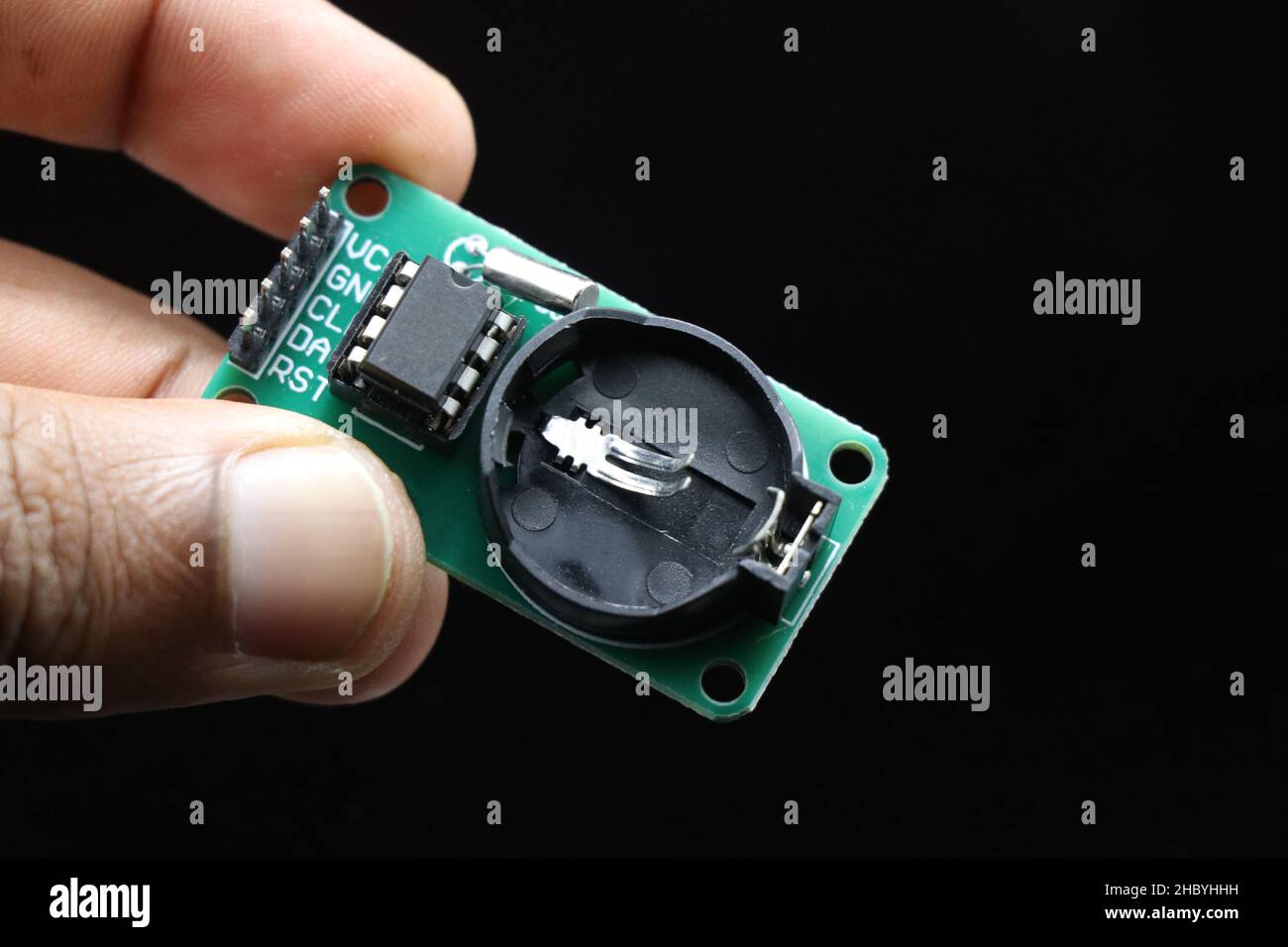 Real time clock module or RTC DS1302 module held in hand isolated on black background Stock Photo