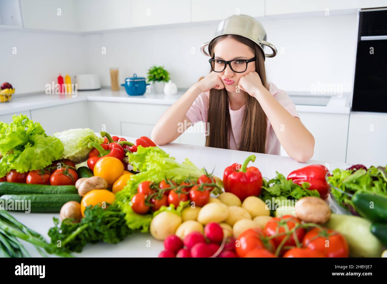 Portrait of attractive funny moody long-haired girl cooking fresh lunch bio farm menu weight loss at home light white kitchen house indoors Stock Photo