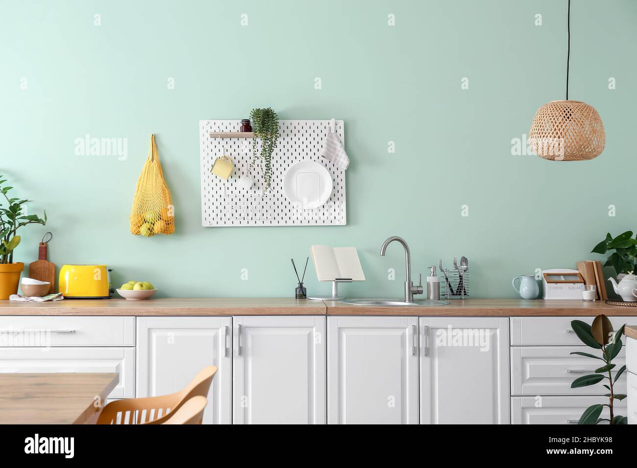 Interior of stylish kitchen with white counters and hanging peg board ...