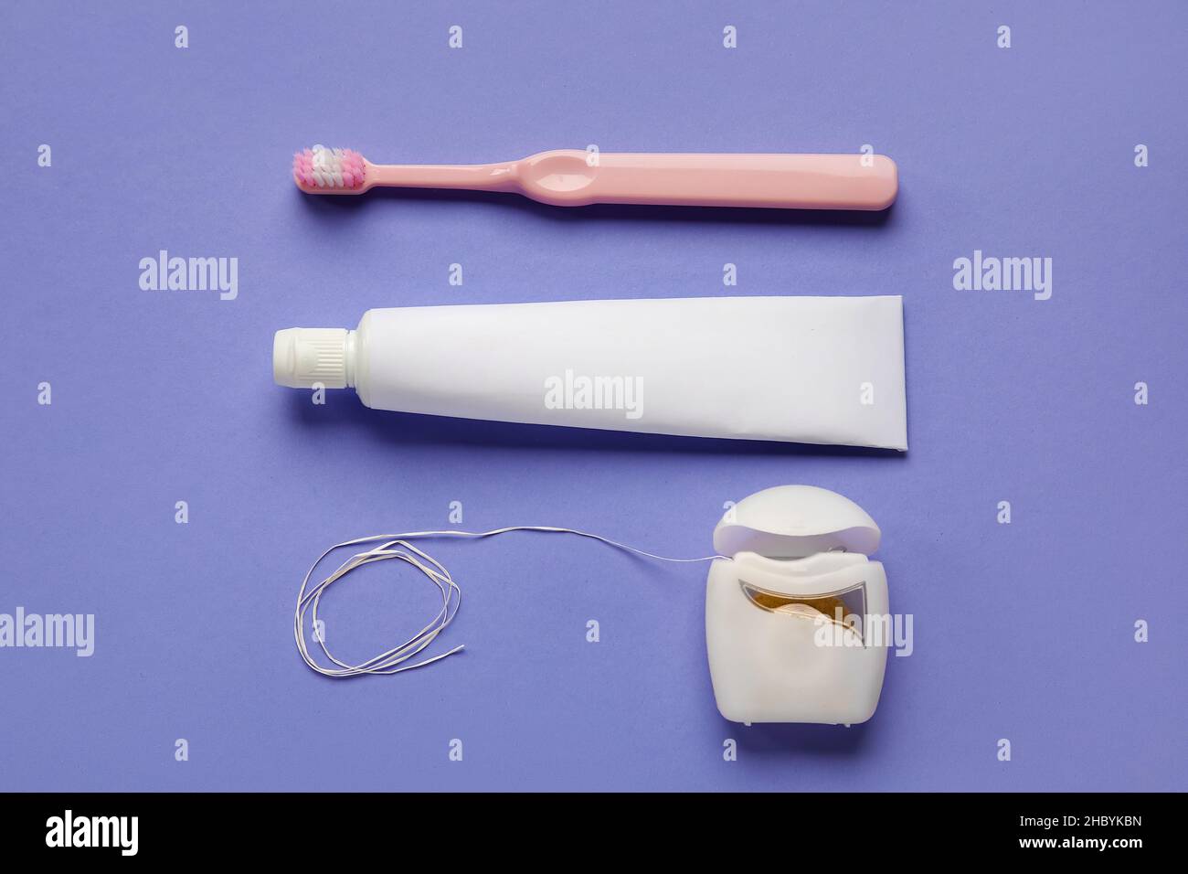 Dental floss with tooth brush and paste on purple background Stock