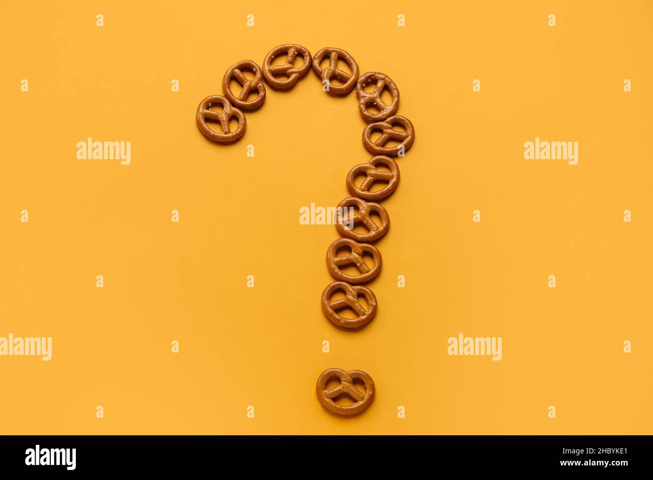 Question mark made of mini pretzels on orange background Stock Photo