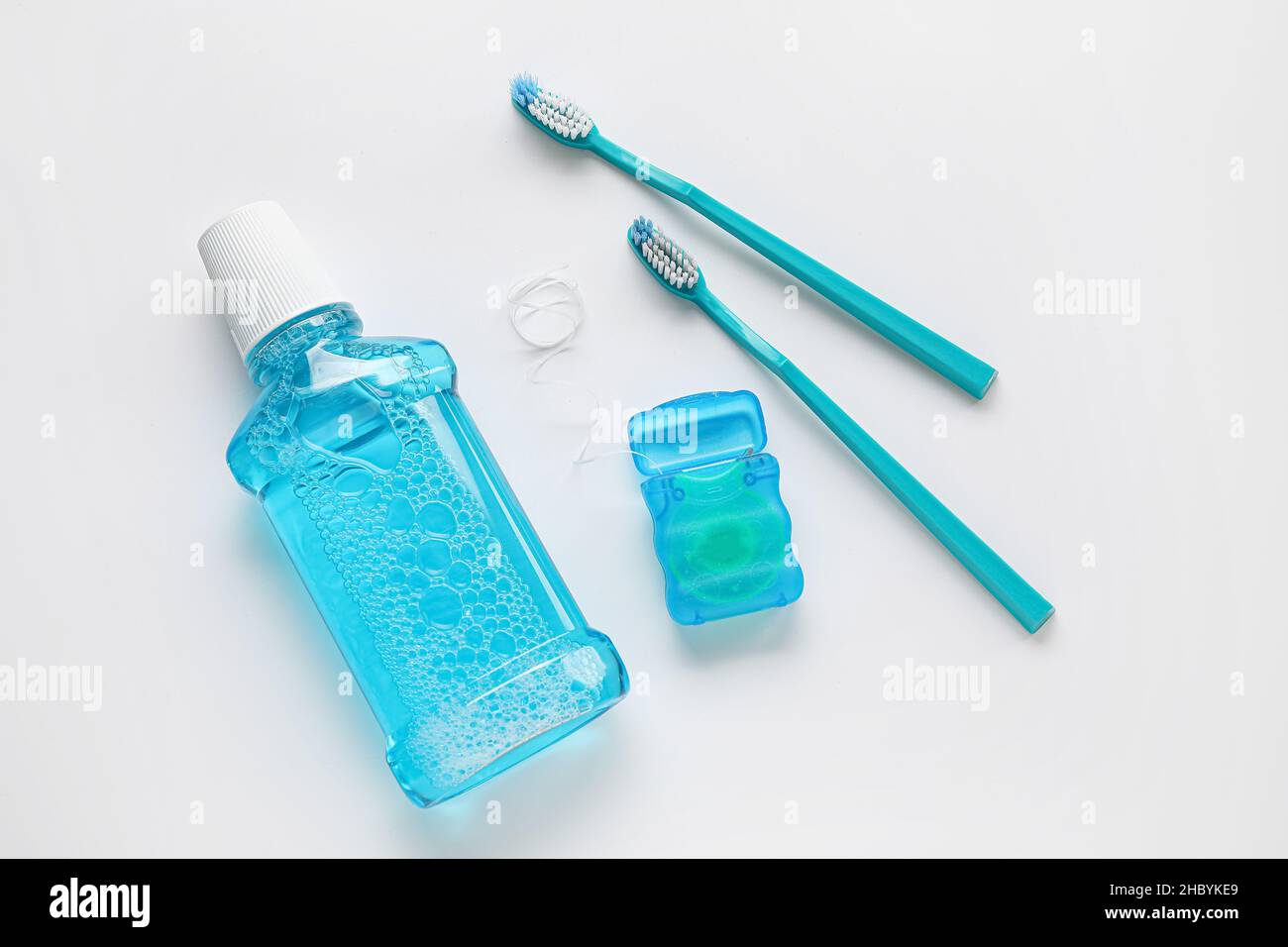 Dental floss with tooth brushes and rinse on white background