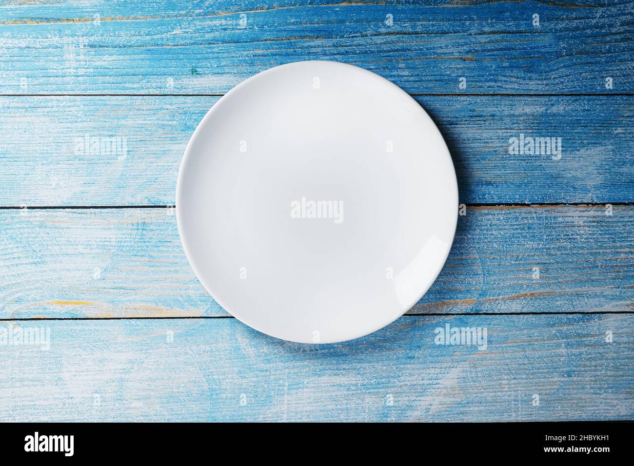 White plate on a blue background top view. Minimalistic concept Stock Photo