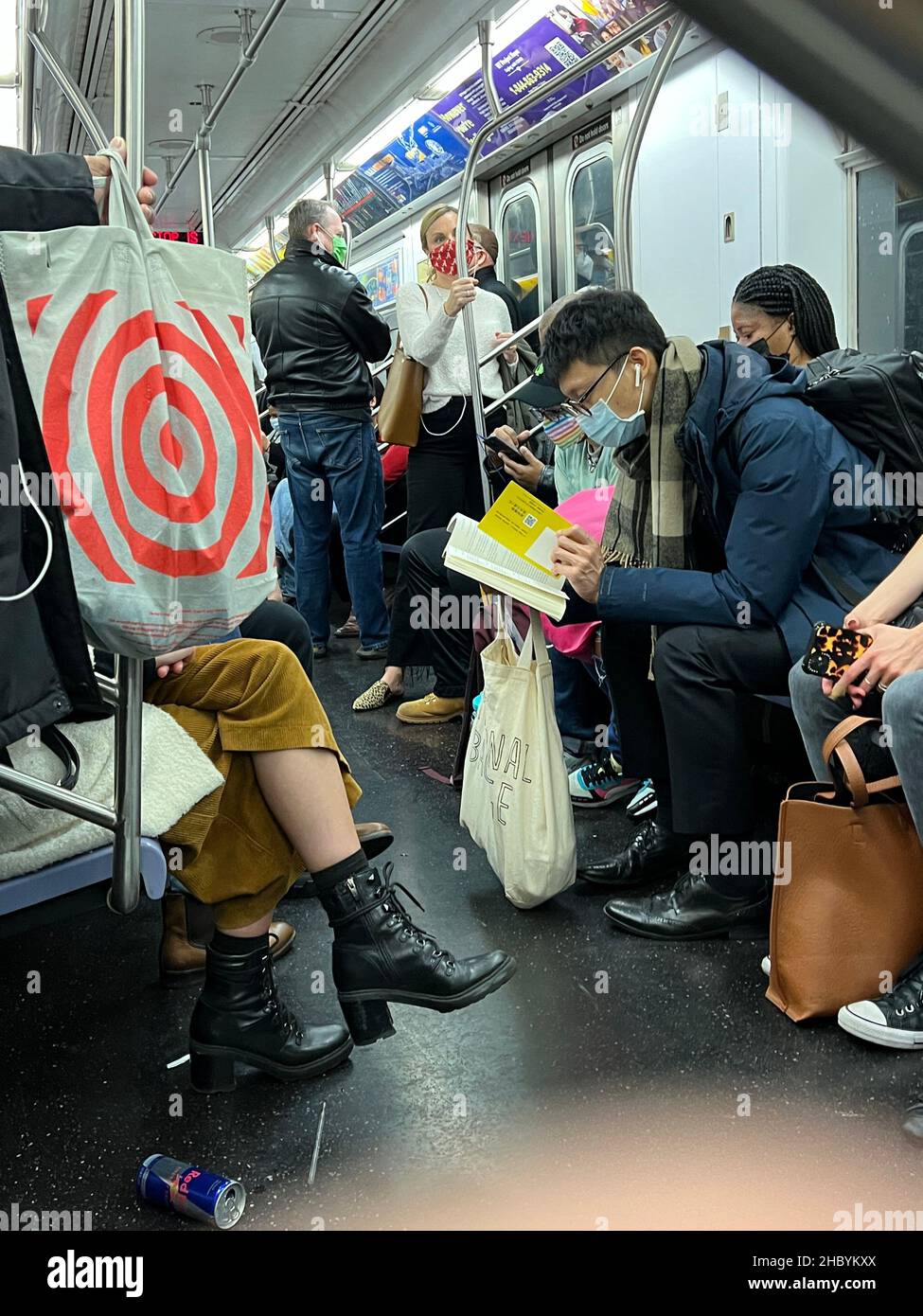 People riding a New York City subway train in face masks but unable to social distance very well  toward the end of the 2nd year of the Covid-19 pandemic. Stock Photo