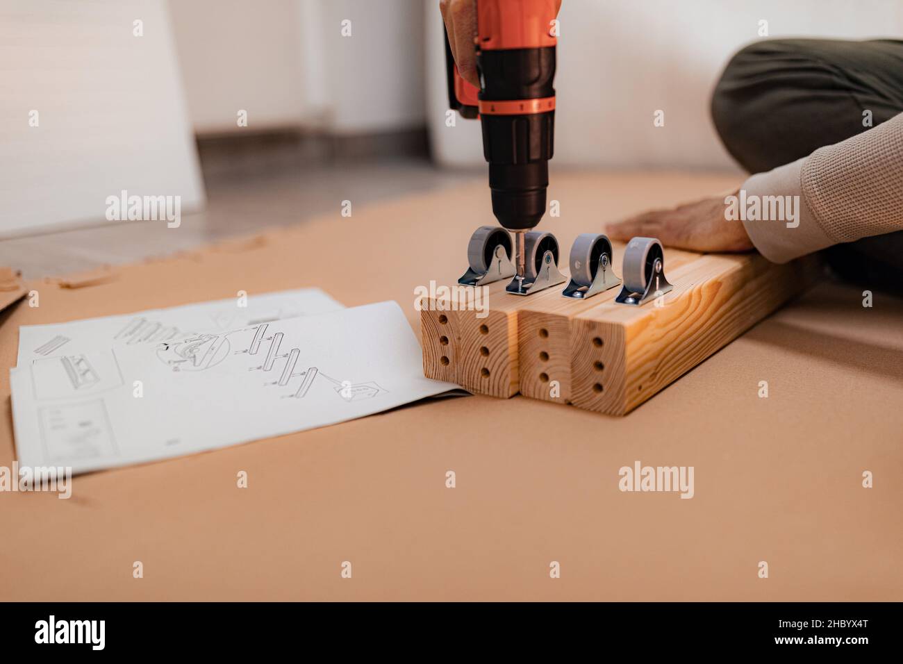 Man working on a new bed installation and using a cordless drill Stock Photo