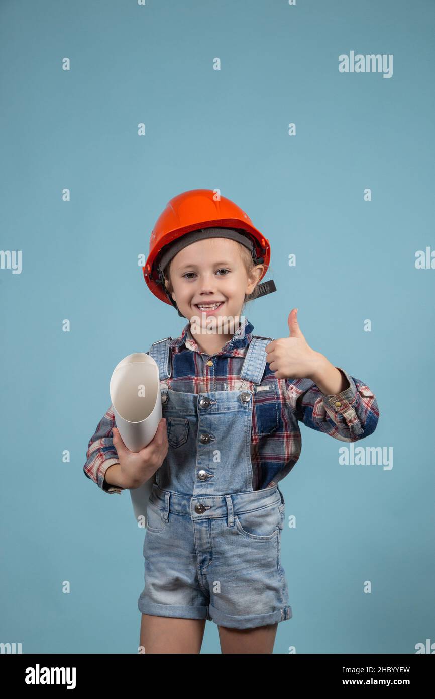 An adorable girl in an orange hard hat posing funny holding wrenches Stock Photo