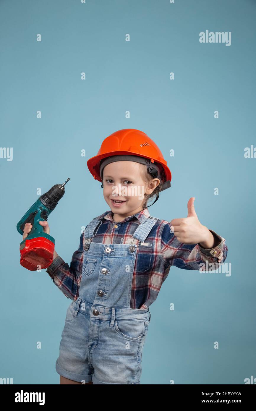 Happy caucasian girl in orange safety helmet,holding screwdriver at hands Stock Photo
