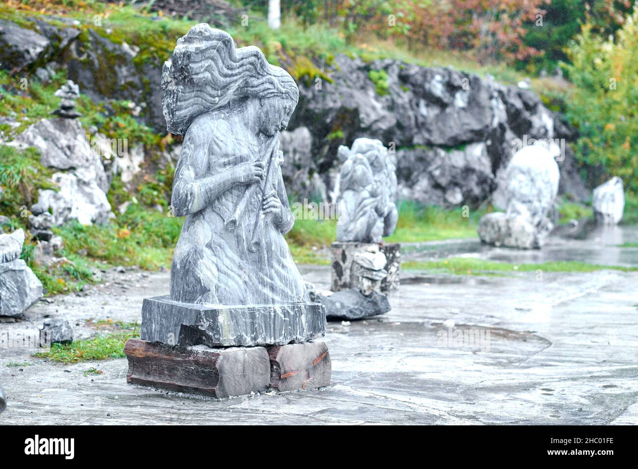 Ruskeala, Russia - 09.14.2021: Marble sculpture of a curly-haired girl playing the flute. Blurred background, art bokeh effect Stock Photo