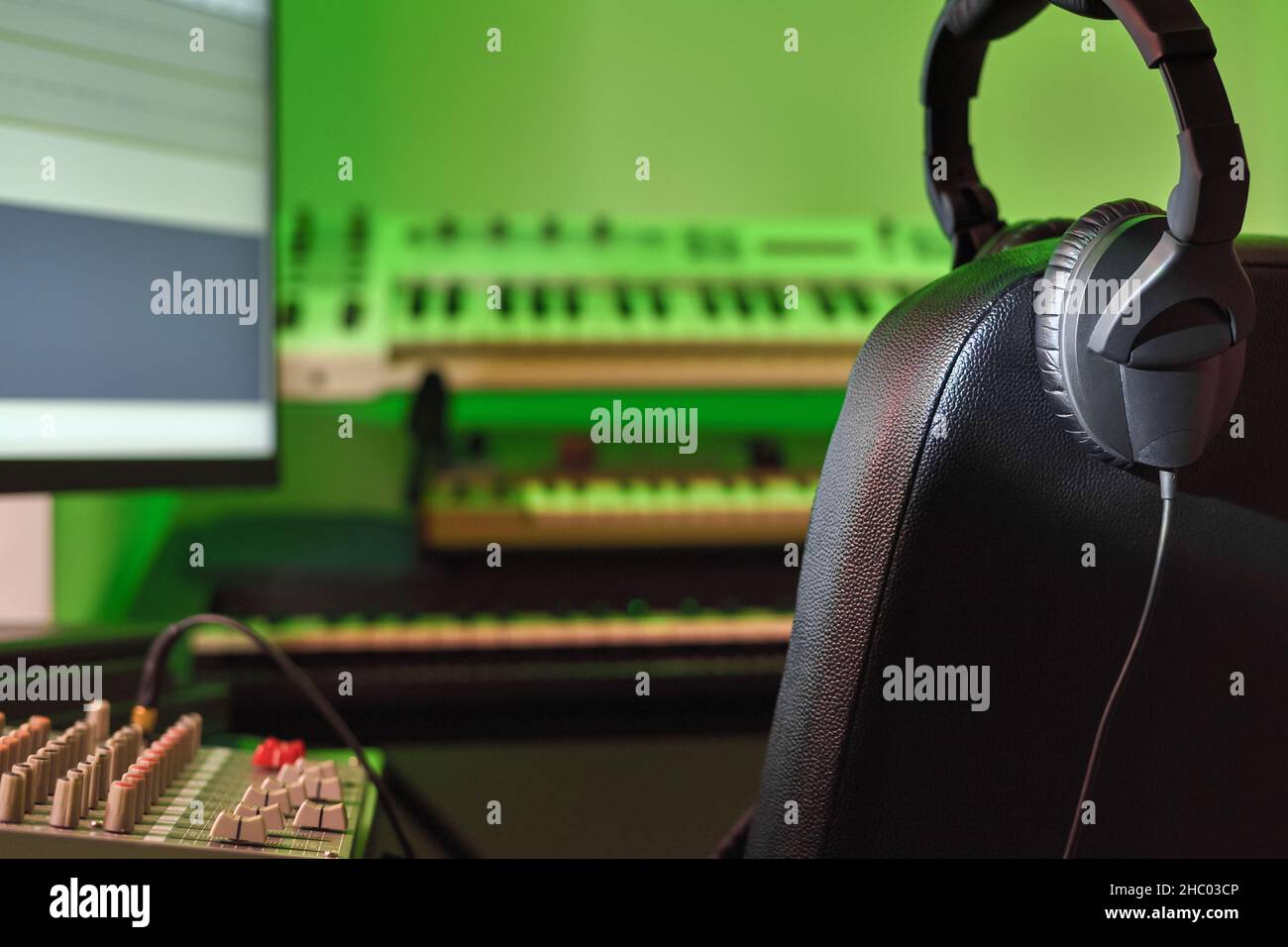Professional headphones in a music recording studio against a background of blurry synthesizers and electronic musical instruments. Recording studio, Stock Photo