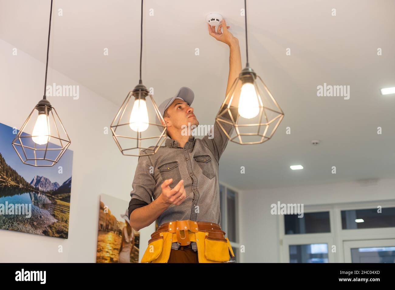 Handyman installing a smoke detector on the ceiling Stock Photo