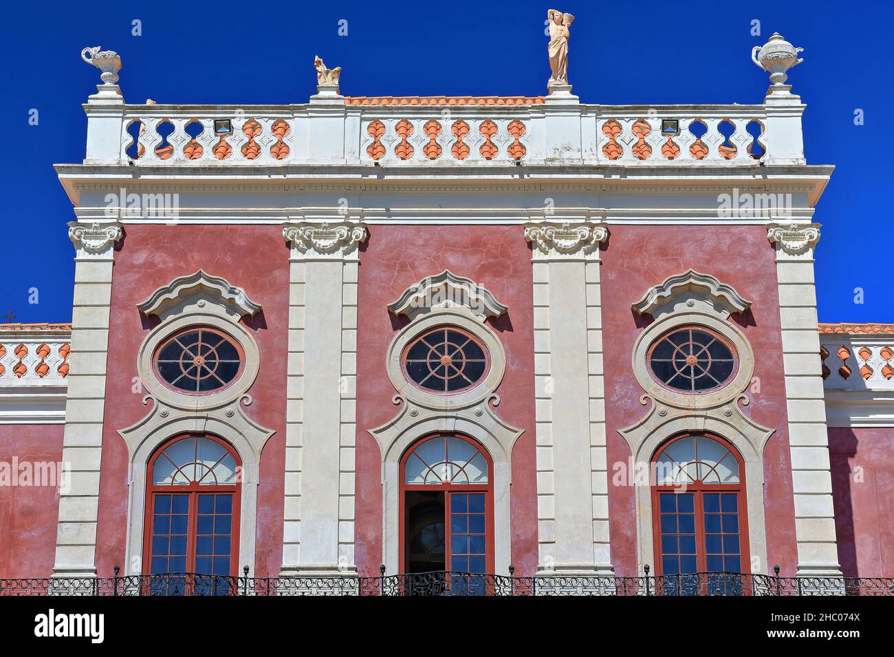 NeoRococo palace-pink facade facing south-long iron balcony-white balustrade-rooftop statues. Estoi-Algarve-Portugal-031 Stock Photo