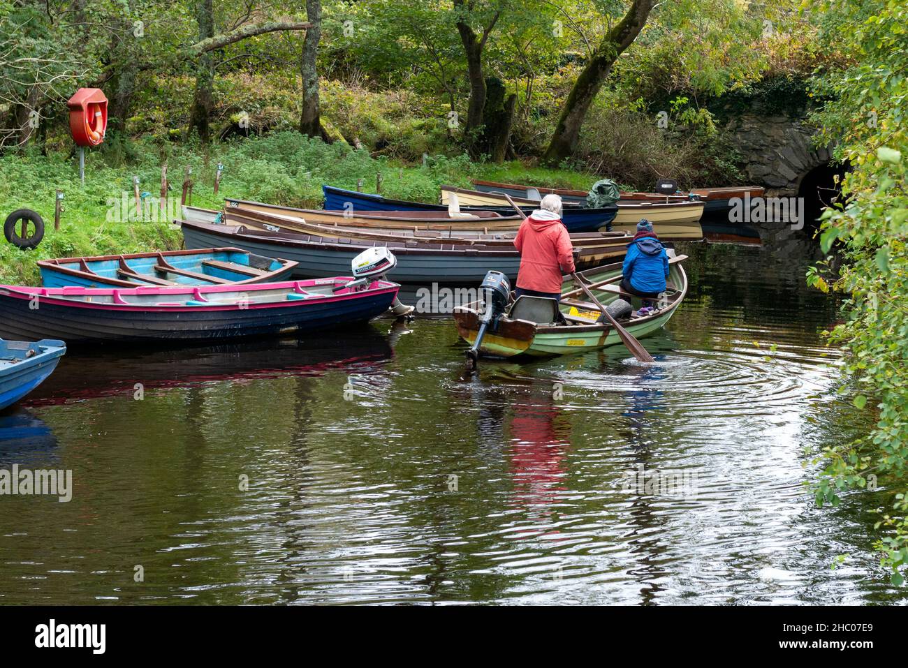 Retirees paddling on a clinker boat in small lake inlet in Killarney