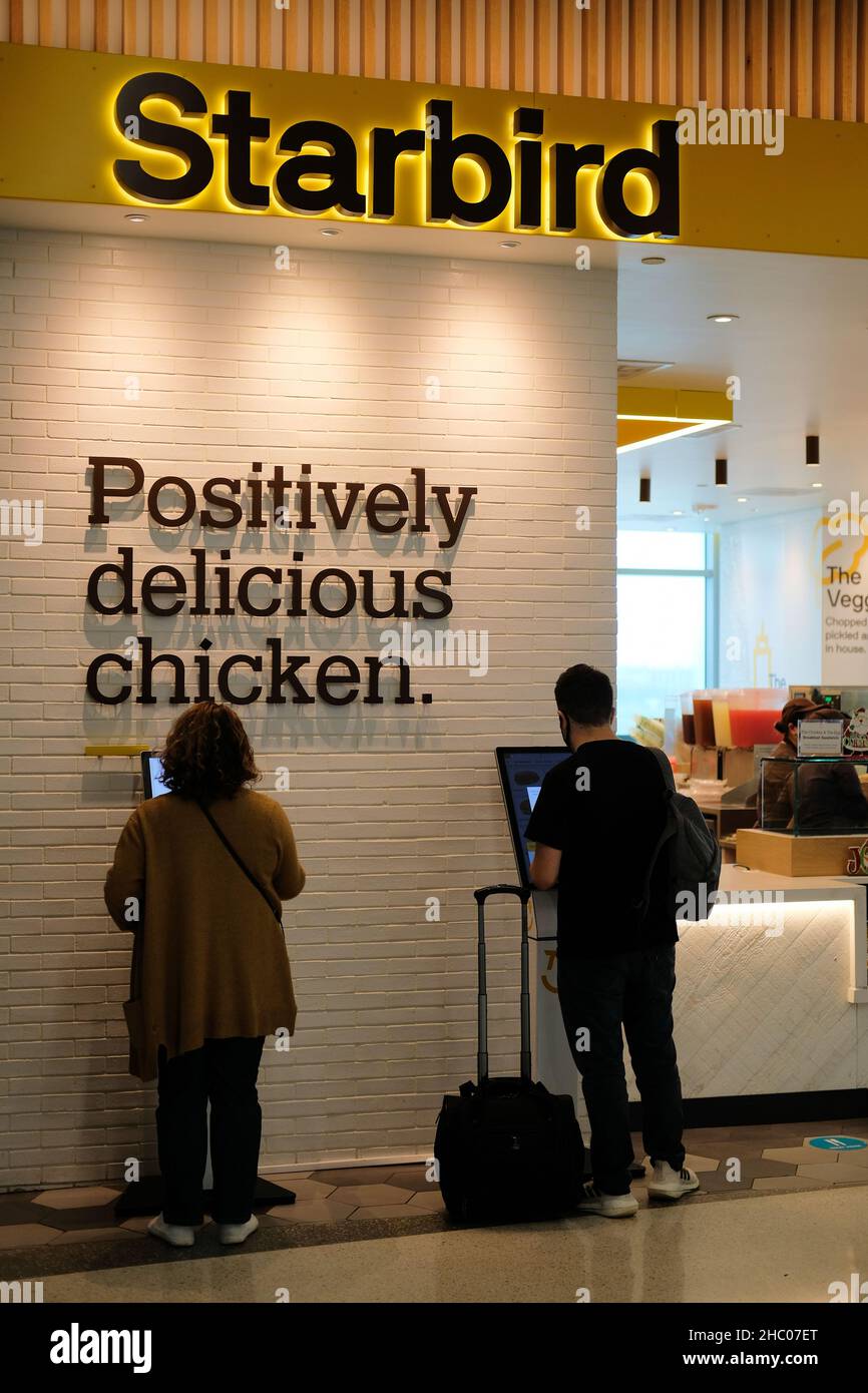 Customers at Starbird Chicken restaurant ordering food at a kiosk at San Francisco International Airport in California; a premium fast food eatery. Stock Photo