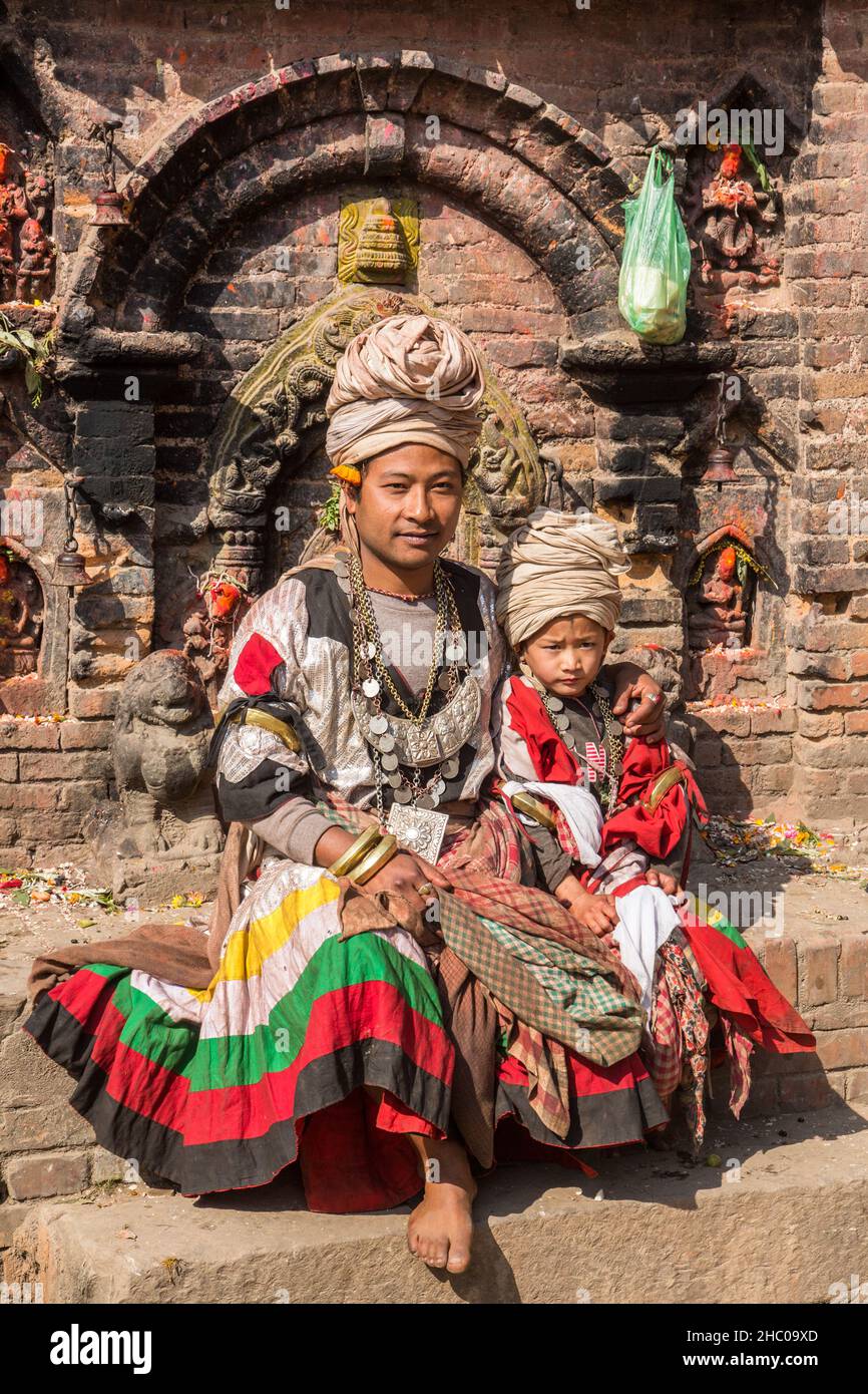 A father and son as costumed and turbaned dancers at the Navadurga Dance Festival in Bhaktapur, Nepal.  They sit in front of a Hindu shrine. Stock Photo