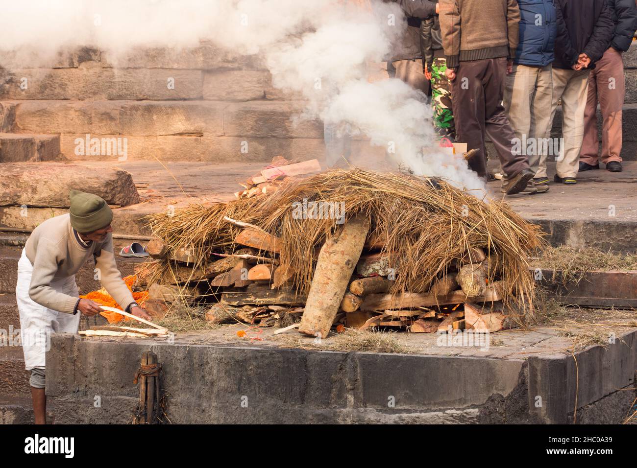 A worker adds wood to the funeral pyre at the Pashupatinath temple