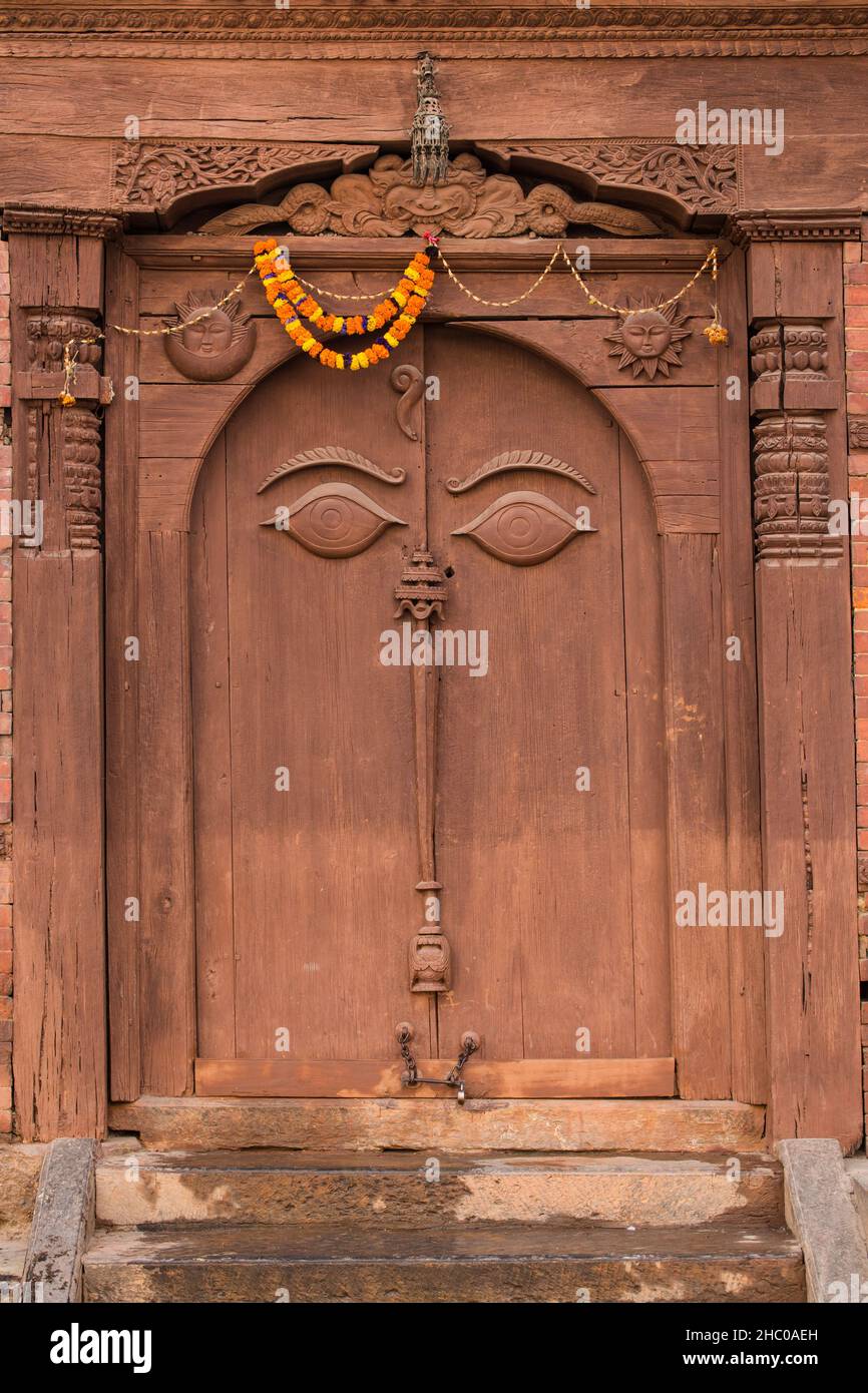 All-seeing eyes on a carved wooden door in the Nasal Chowk of the Hanuman Dhoka Durbar Square.  Kathmandu, Nepal.  Above the doorway is a carving of G Stock Photo