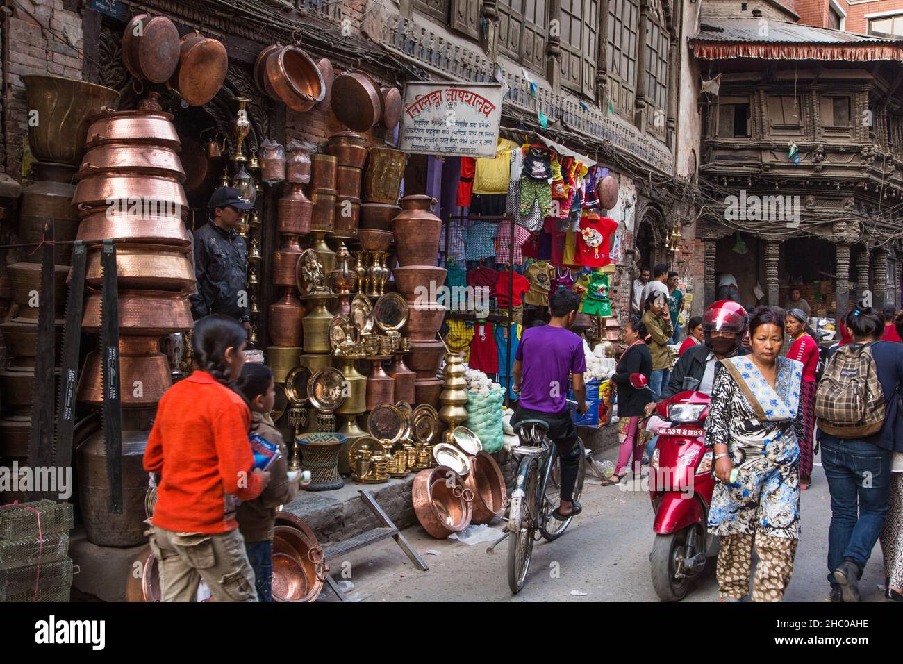 A busy street scene in front of a shop selling copperware in a neighborhood in Kathmandu, Nepal. Stock Photo