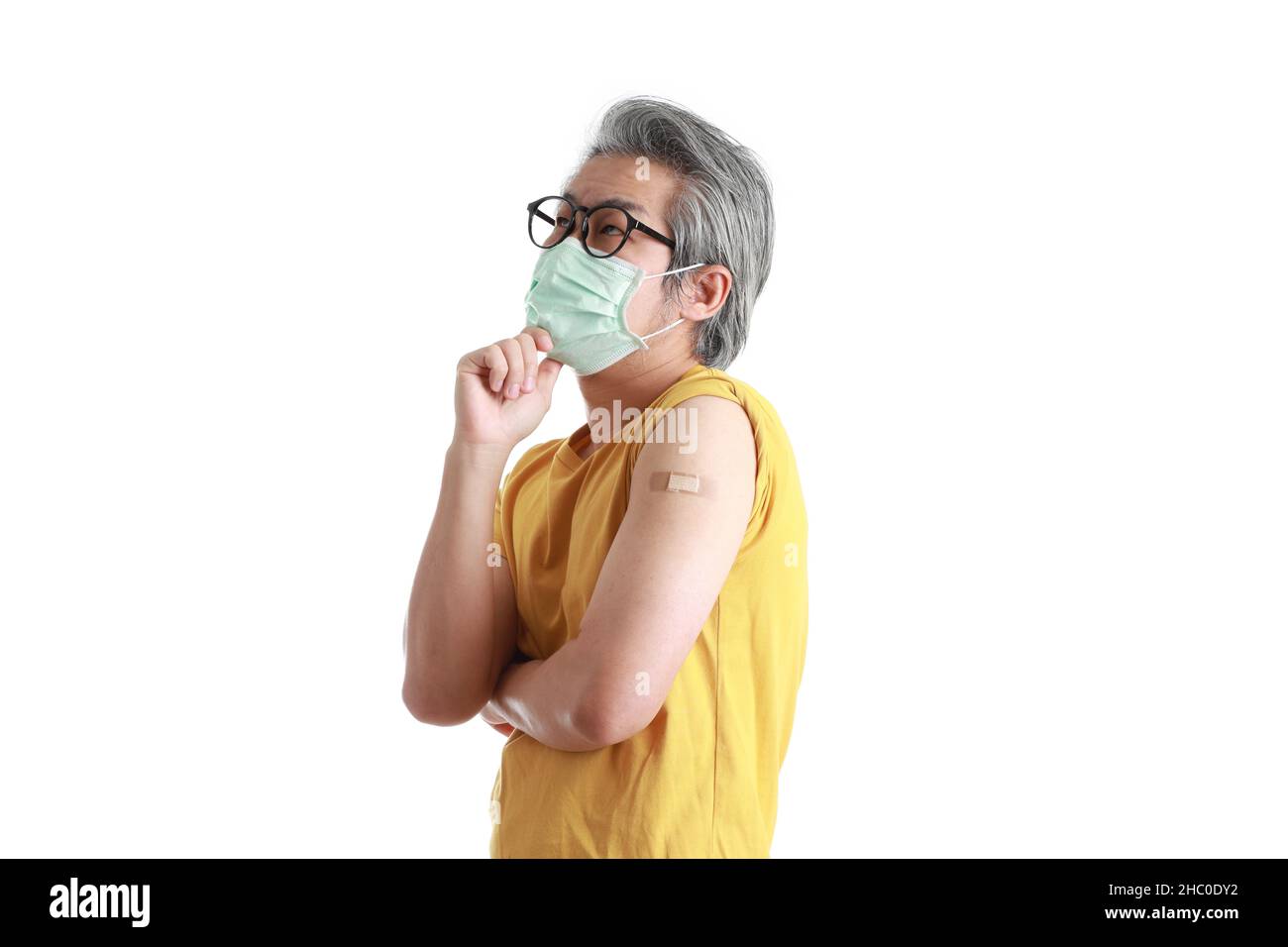 The senior Asian man with mask showing plaster on his shoulder Stock