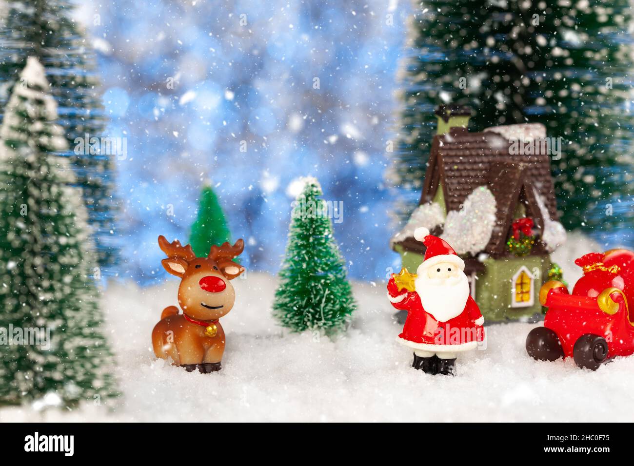 Toy santa claus and sleigh in the snow, artificial fir trees around ...