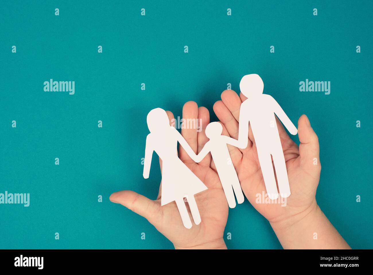 Parents with one child holding hands, paper cut out, copy space, petrol colored background, relationship Stock Photo