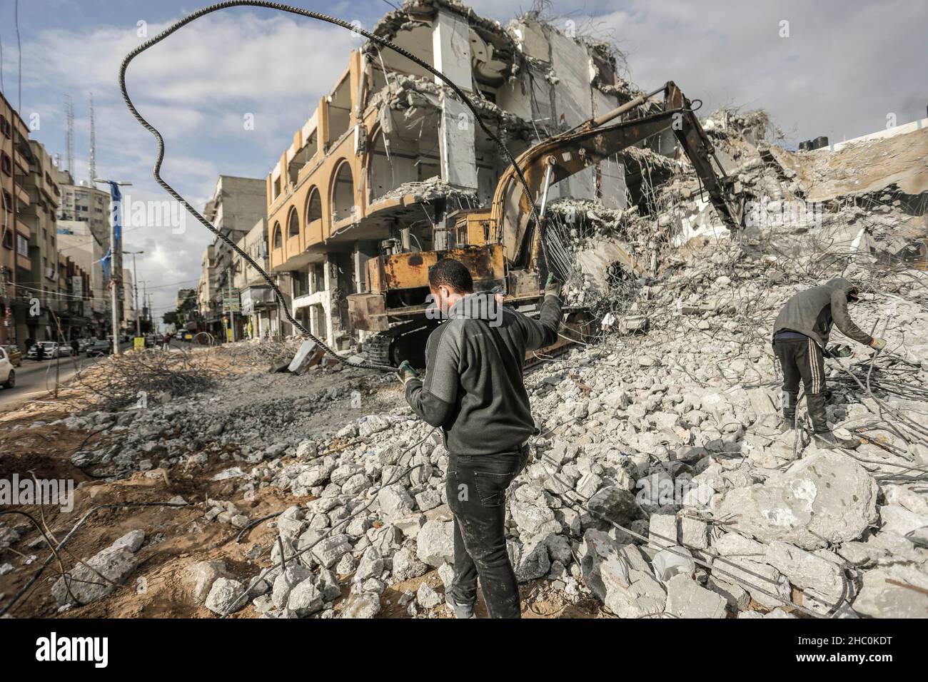 Palestinian workers remove the rubble with a bulldozer from Al-Jawharah ...
