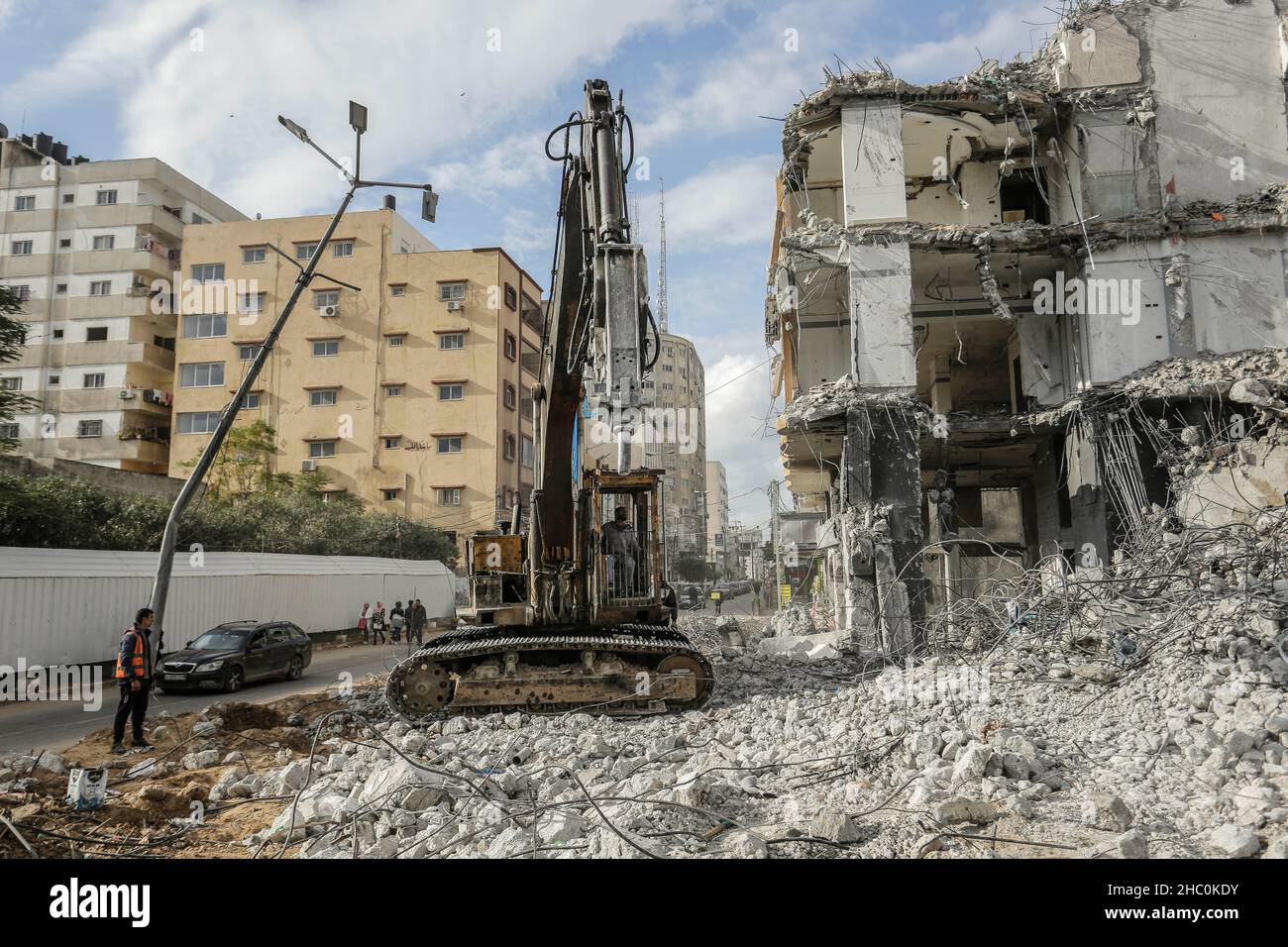 Palestinian workers remove the rubble with a bulldozer from Al-Jawharah ...