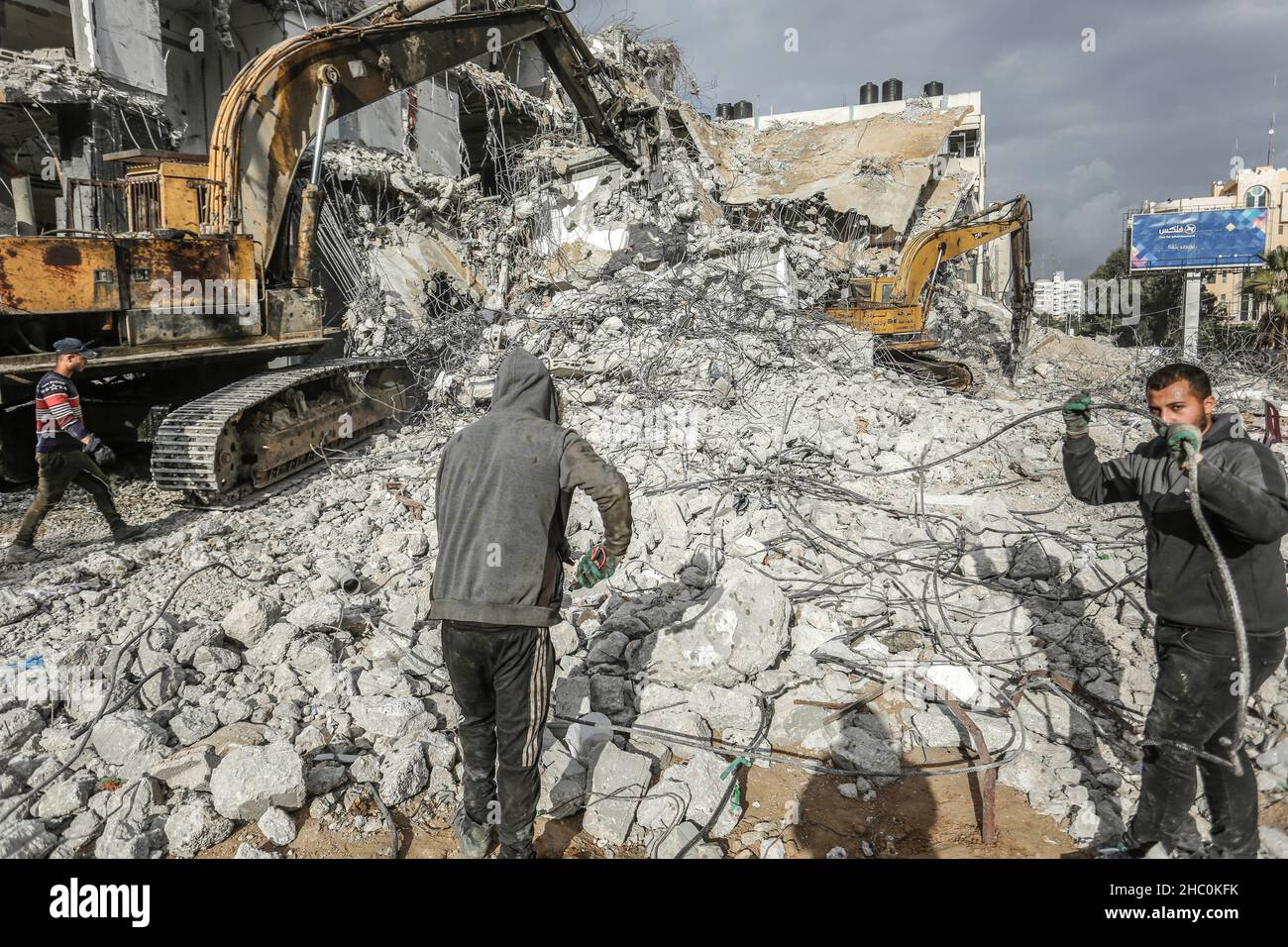 Palestinian workers remove the rubble with a bulldozer from Al-Jawharah ...