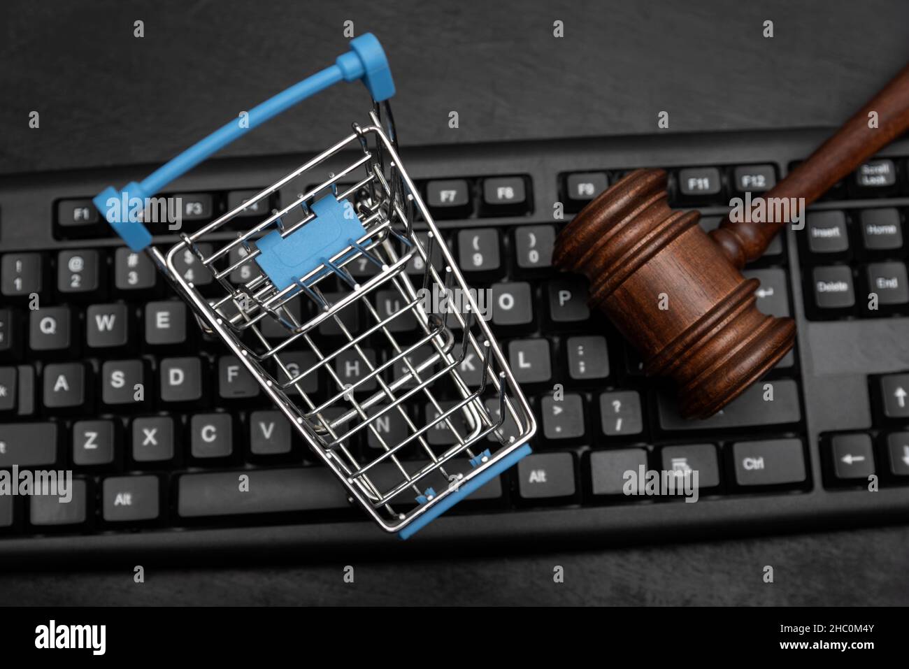 Shopping cart and judges hammer on the keyboard. Online Auction Stock Photo