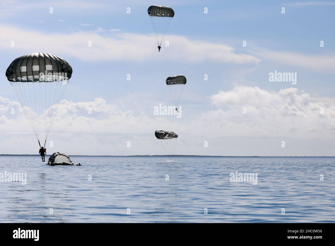 U.S. Army Reserve paratroopers from across the U.S. Army Civil Affairs and Psychological Operations Command (Airborne) descend into Biscayne Bay, Miami-Dade County Nov. 19, 2021, as part of a Deliberate Water Jump. The jump was the concluding event of the Army Reserve Airborne Safety Equipment and Evaluation Council held in Homestead, Florida.     The weeklong event, hosted by the 478th Civil Affairs Battalion (Airborne), located at Perrine, Florida, 1st Civil Affairs and Psychological Operations Training Brigade, included a Jumpmaster Refresher course, the AR-ASEEC, airborne operations at Hom Stock Photo