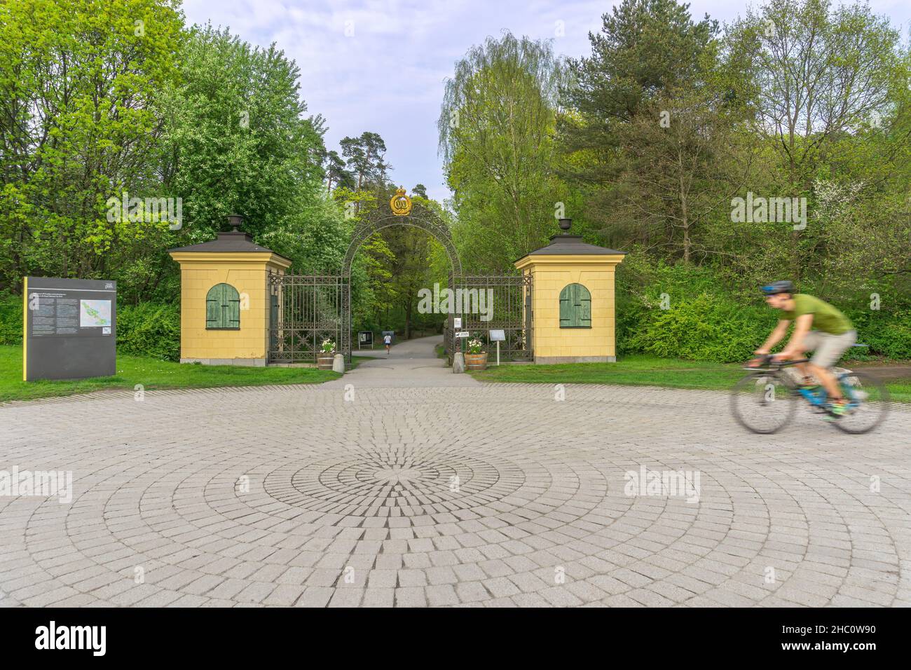 Stockholm, Sweden - May 13, 2021: Entrance to the big park in the middle of Stockholm with one blurred cyclist passing the entrance Stock Photo