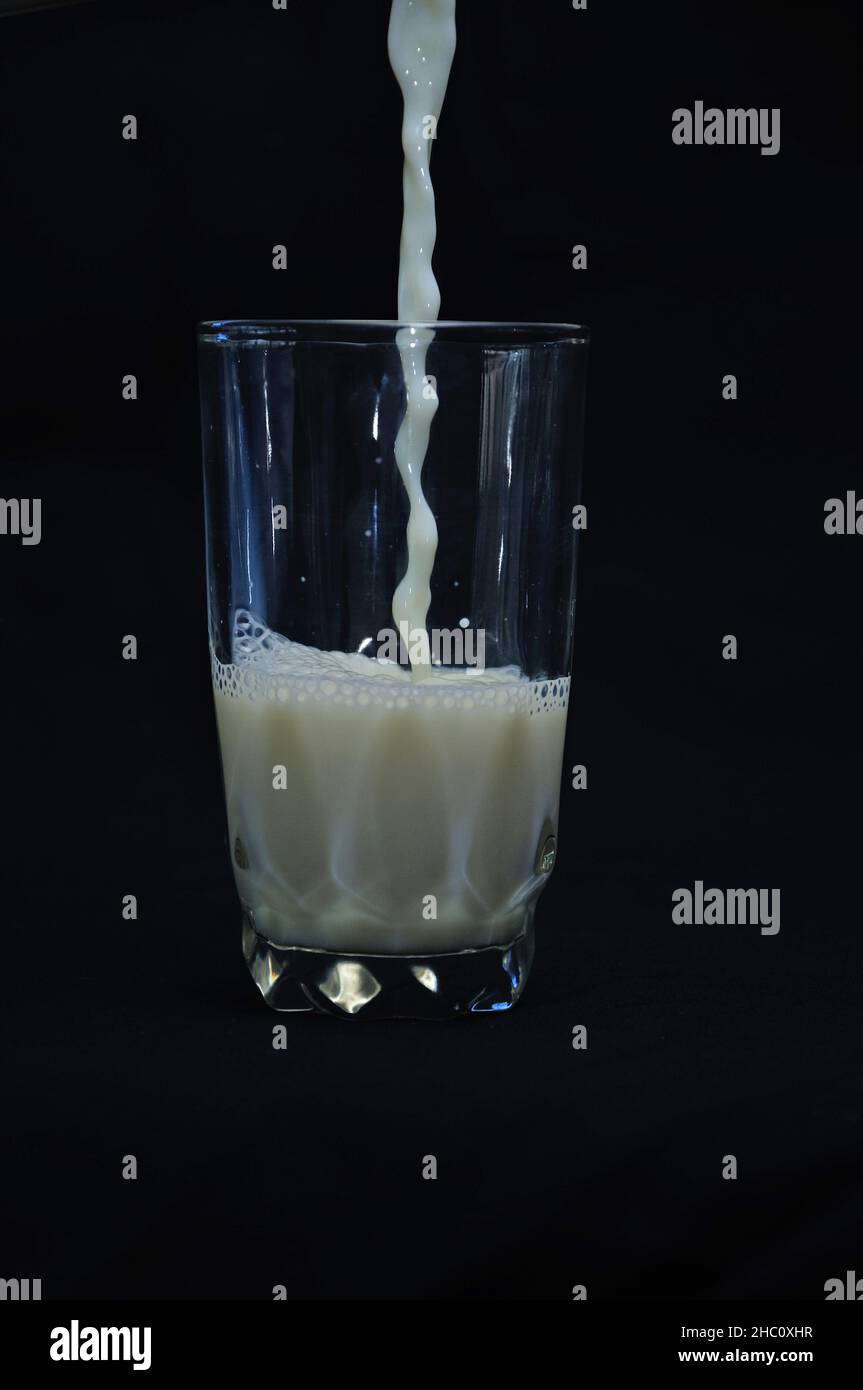 Pouring fresh milk into a glass against a black background Stock Photo