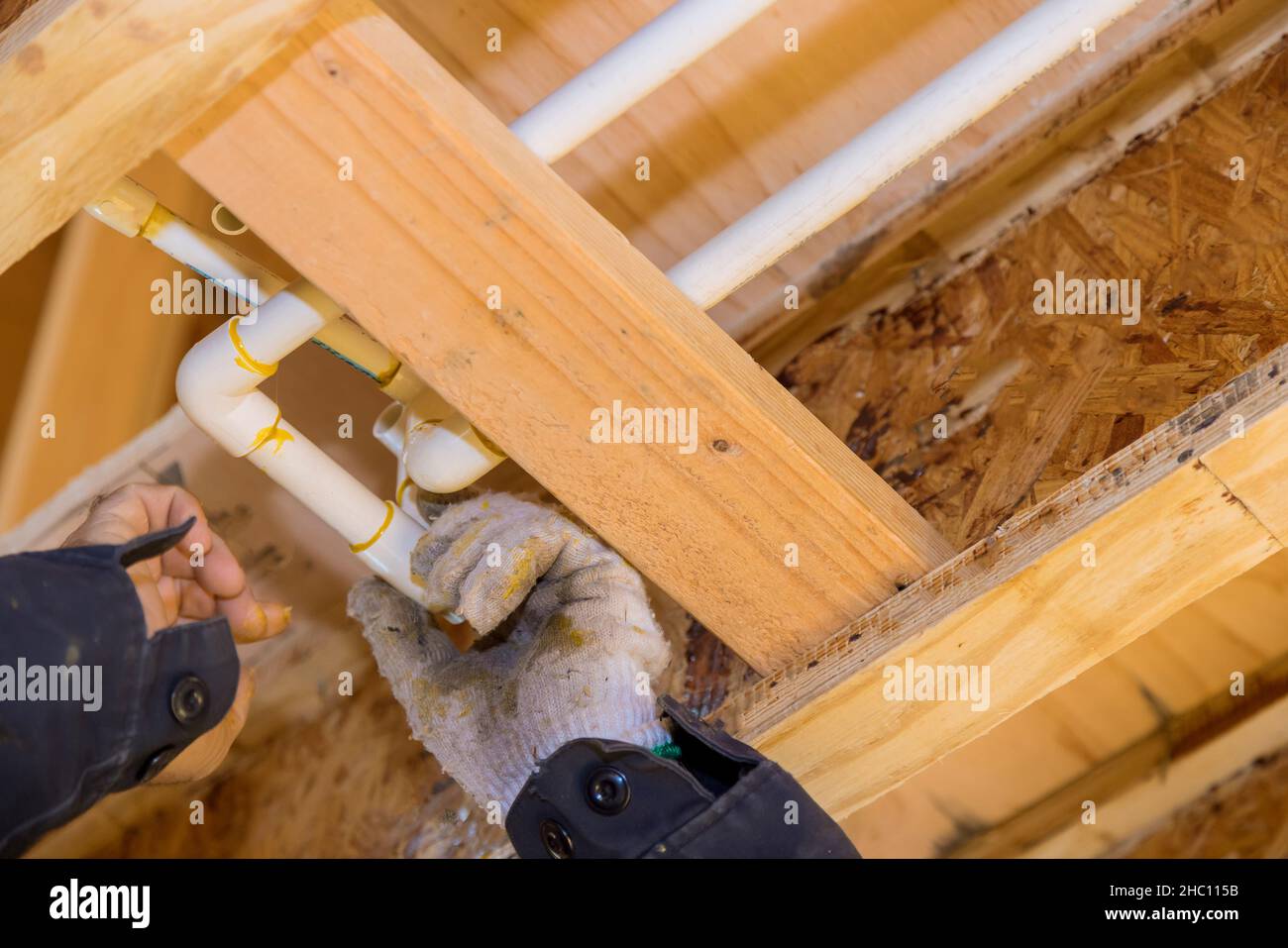 A plumber in a plastic water pipe into putting glue on a PVC