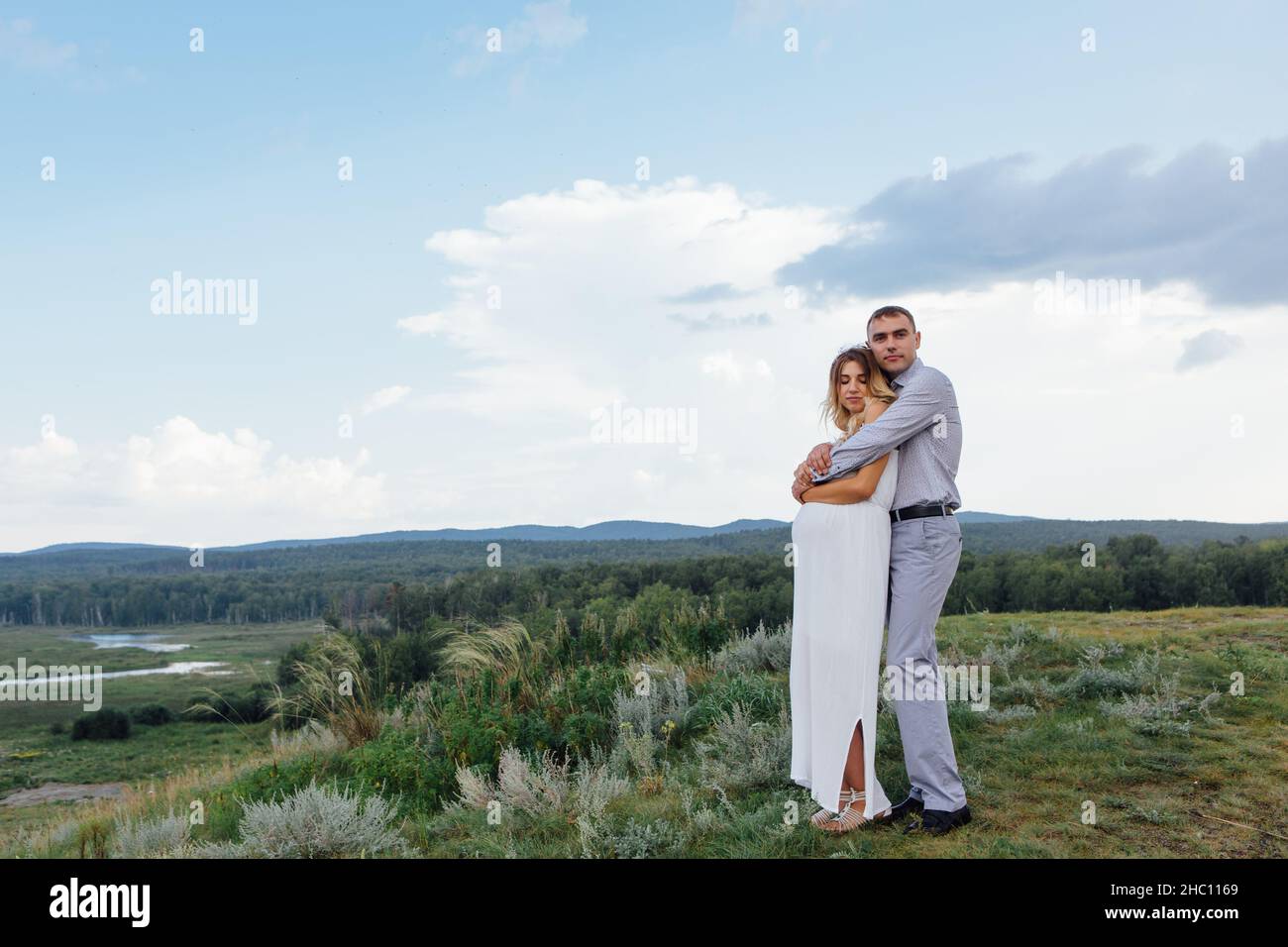 Happy young couple, expecting a baby. Man hugs his pretty pregnant ...