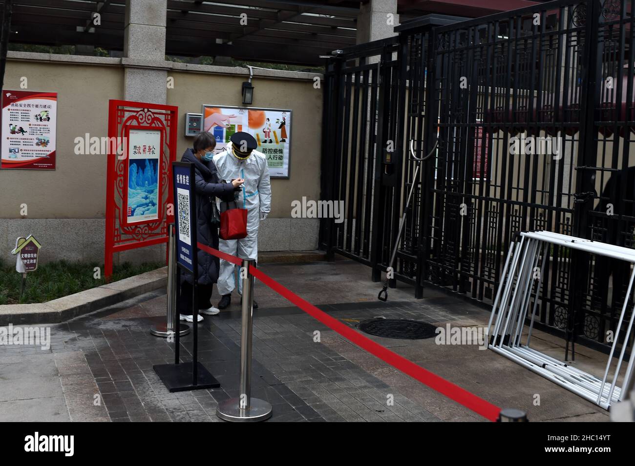 XI'AN, CHINA - DECEMBER 23, 2021 - A staff member checks a work certificate issued by a special industry unit at the gate of a residential community i Stock Photo