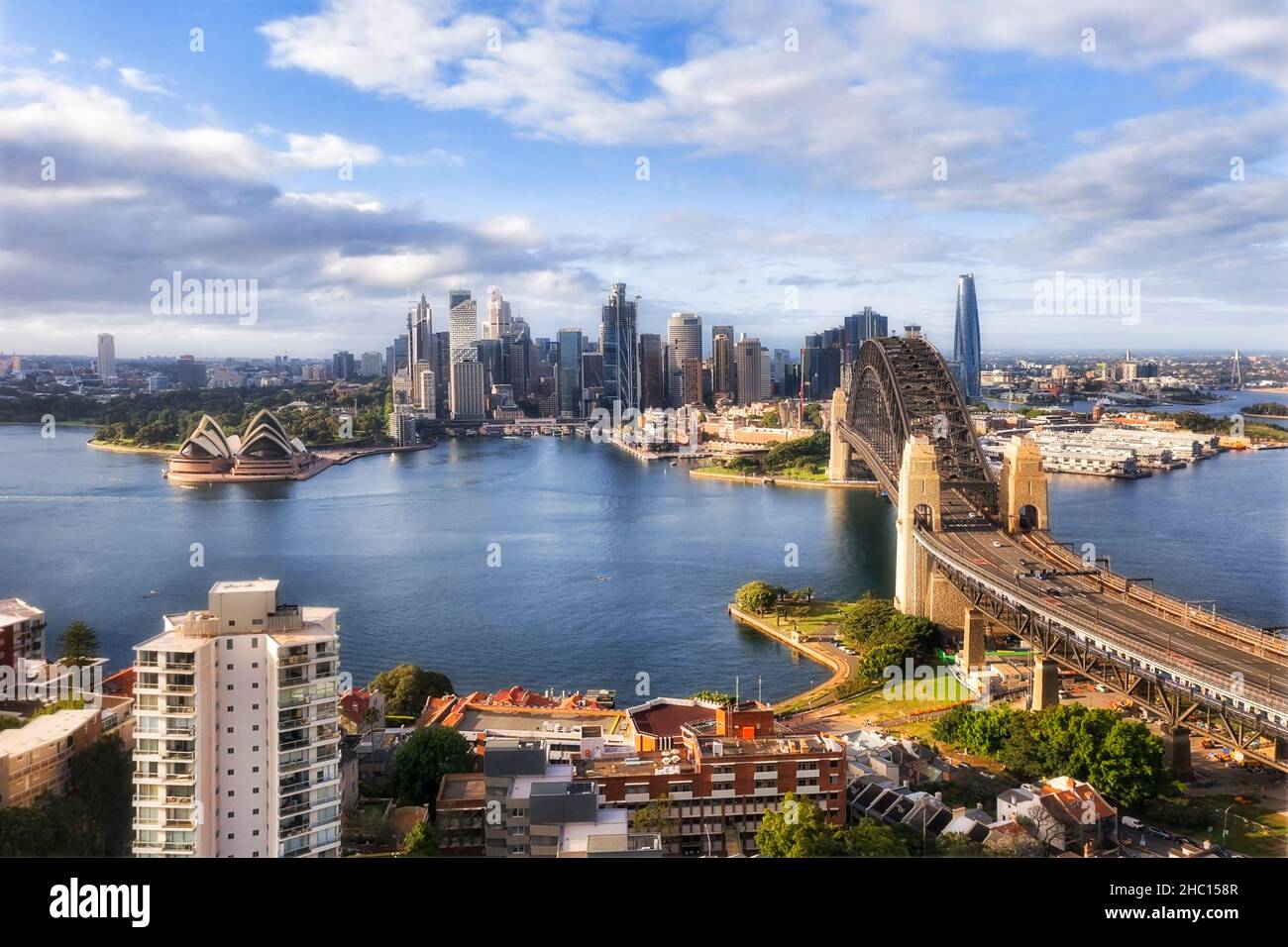 Sydney harbour bridge across harbour connecting NOrth Sydney to city CBD - aerial view of waterfronts. Stock Photo