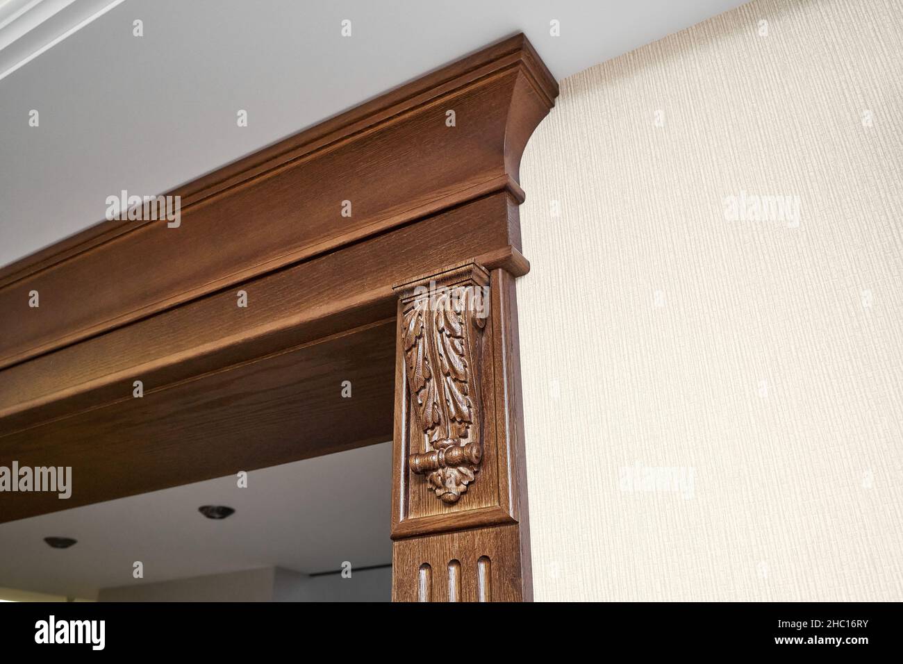 Decorated wooden doorway with carved furniture brackets and fluted panel in classic style in light spacious room closeup Stock Photo