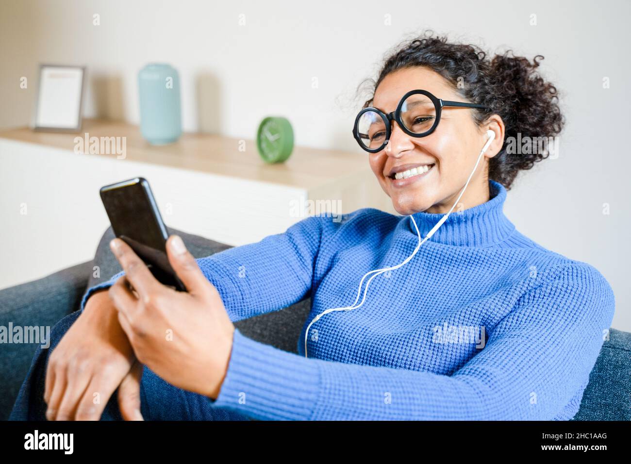 Cheerful black woman listening to music using smartphone Stock Photo