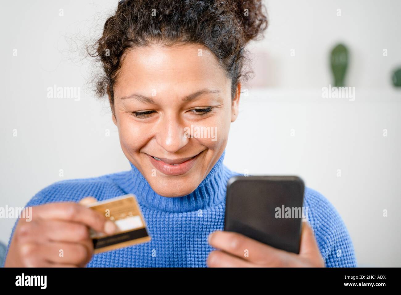 Black woman holding credit card and shopping online at home Stock Photo