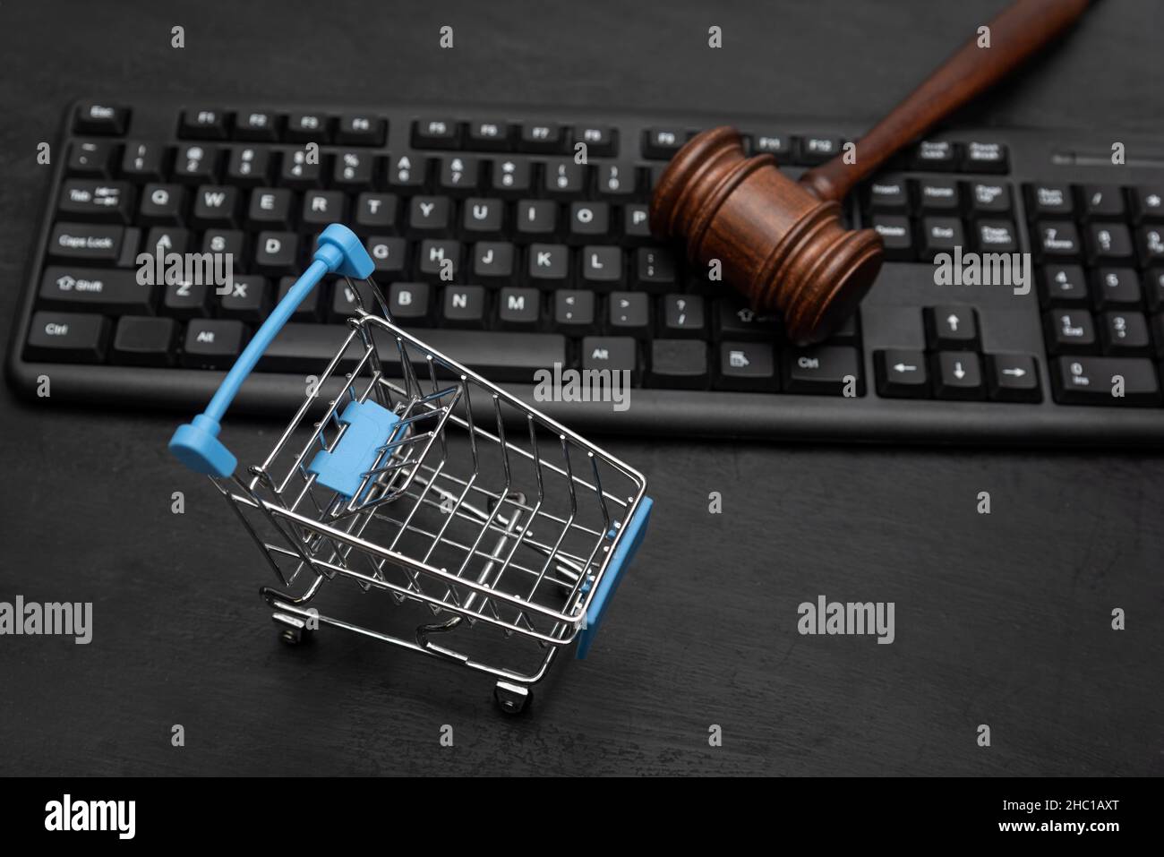 Shopping cart and judge's hammer on the keyboard. Litigation with the seller. Black background Stock Photo