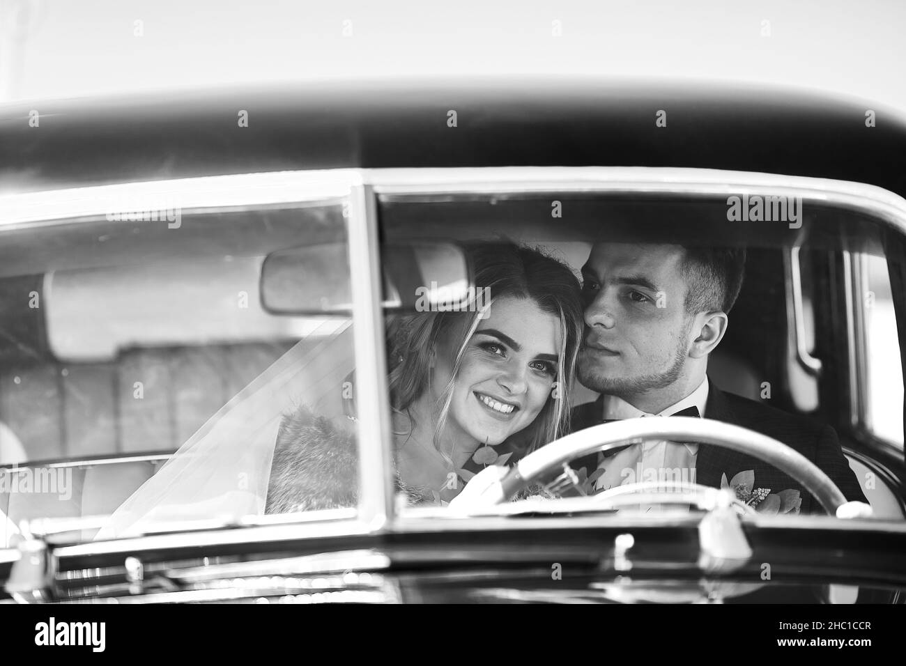 Happy bride and groom hugging and posing near old retro car before wedding ceremony Stock Photo