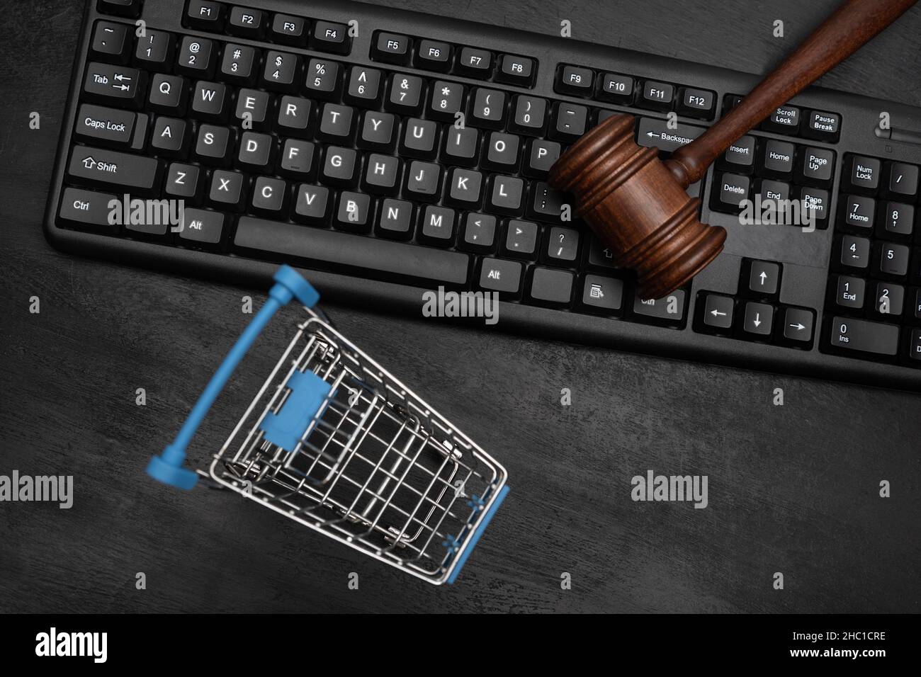 Empty shopping cart and judges hammer on the keyboard. Online Auction Stock Photo