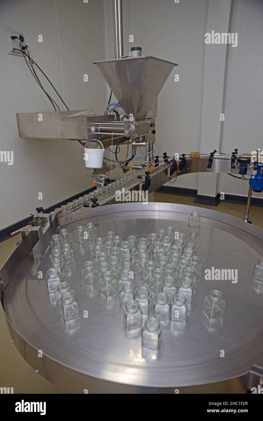 Jars of creamed honey in a packaging line at a commercial honey factory