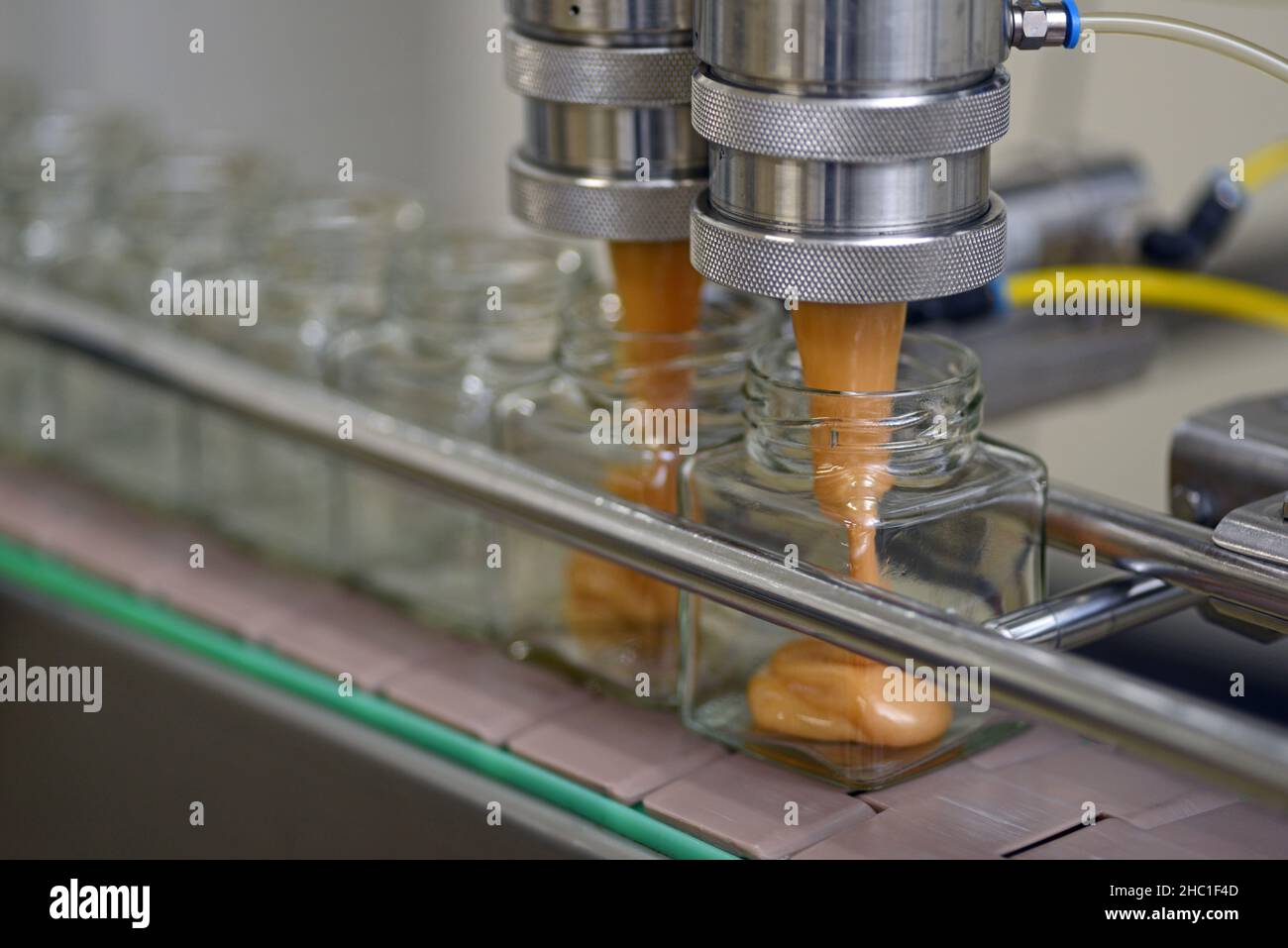 Jars of creamed honey in a packaging line at a commercial honey factory