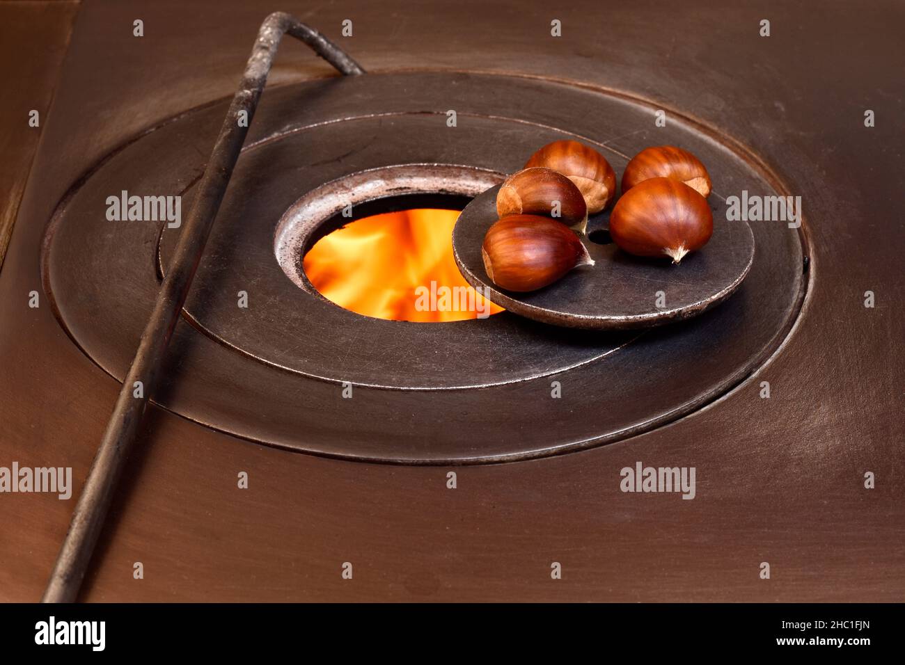 Close-up of five chestnuts on the fire of a wood stove.The photo represents something typical of the autumn season and is taken in horizontal format. Stock Photo