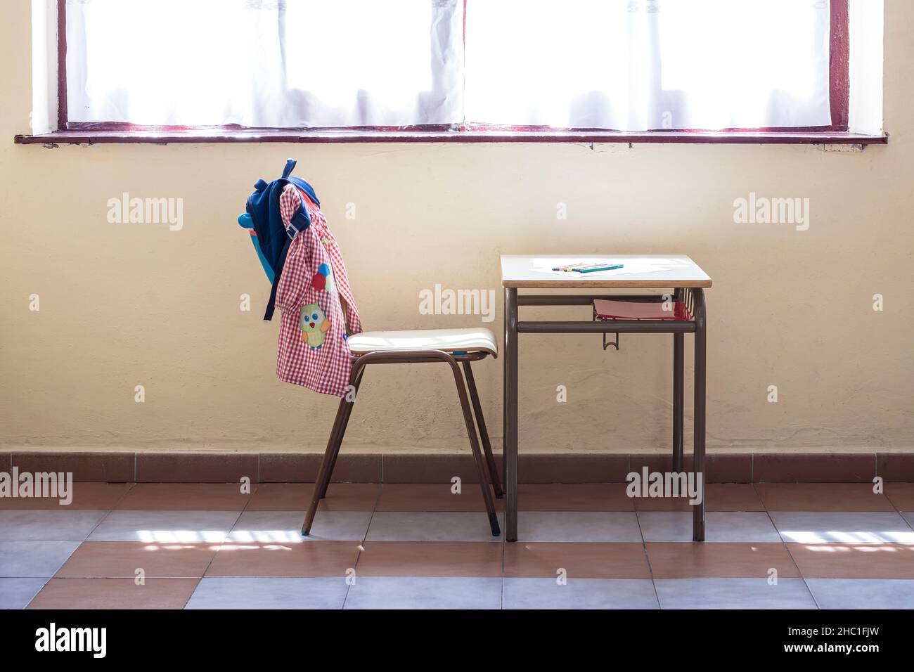 Desk and chair of a nursery school.In the photo you can see the typical material of the school year such as the backpack and the apron of a child.The Stock Photo