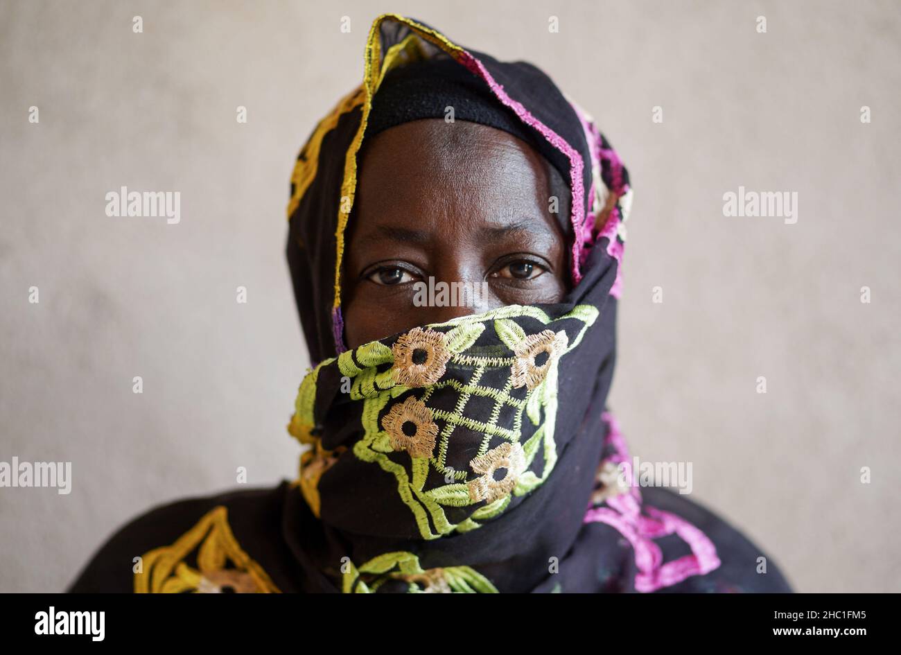 Old black African woman, with mouth head and shoulders covered by a embroidered veil, looking blankly into space; ognitive health in elderly concept Stock Photo