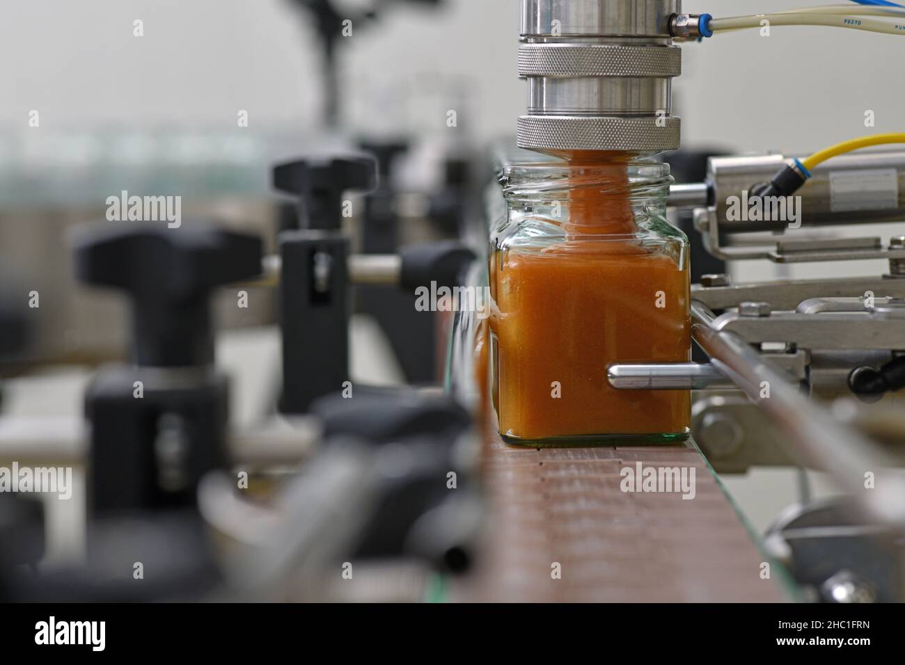 Jars of creamed honey in a packaging line at a commercial honey factory