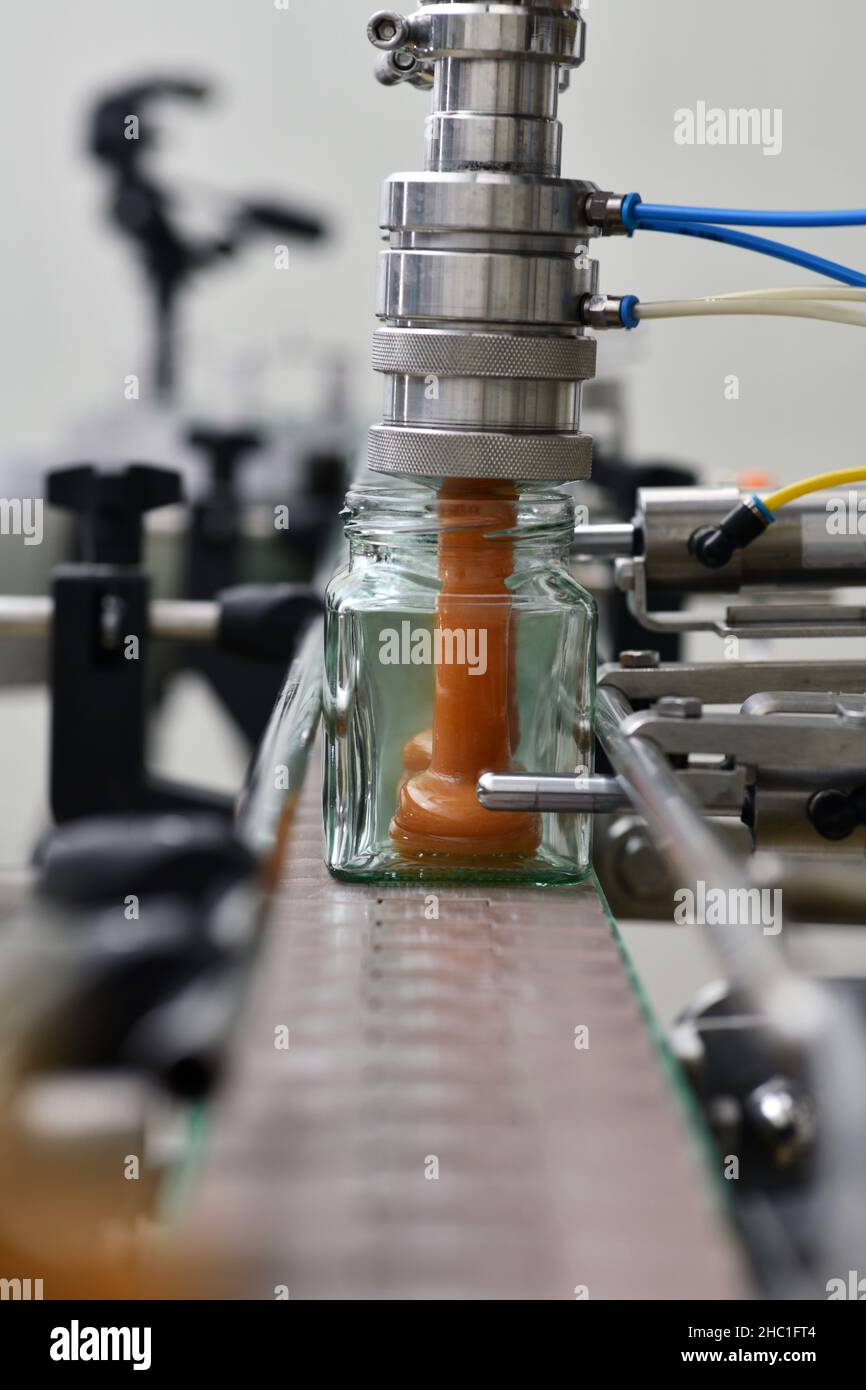 Jars of creamed honey in a packaging line at a commercial honey factory