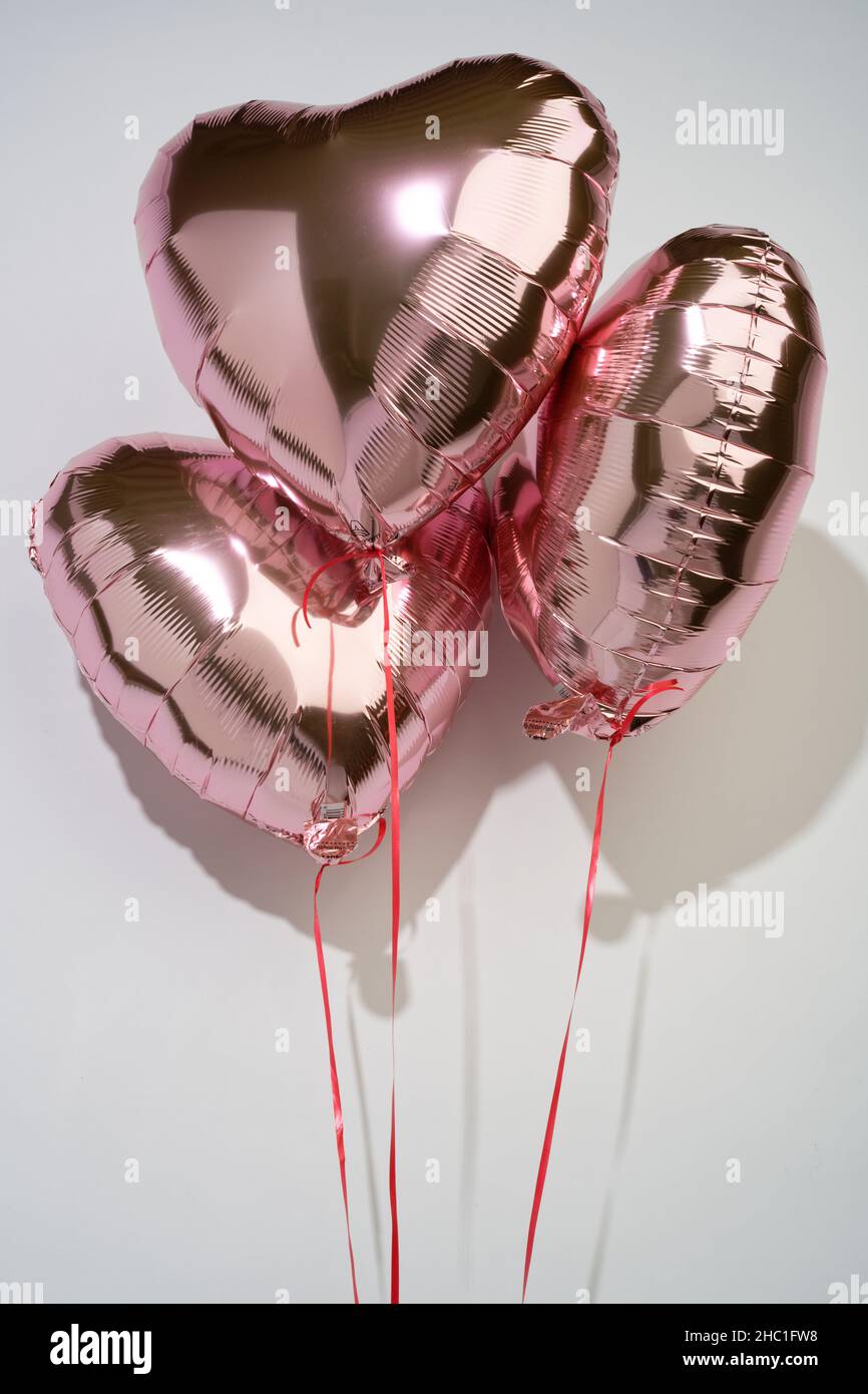 A set of heart shaped love tokens. A gift to show ones love for another. Pink helium balloons. Stock Photo