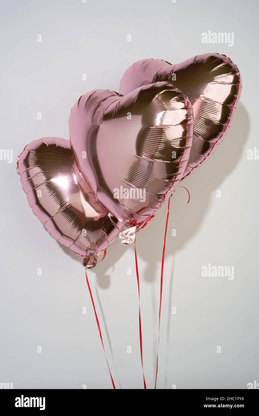 A set of heart shaped love tokens. A gift to show ones love for another. Pink helium balloons. Stock Photo